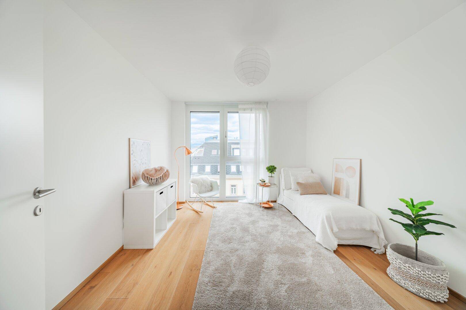 Helles Zimmer mit Holzboden, großem Fenster und minimalistischer Einrichtung.