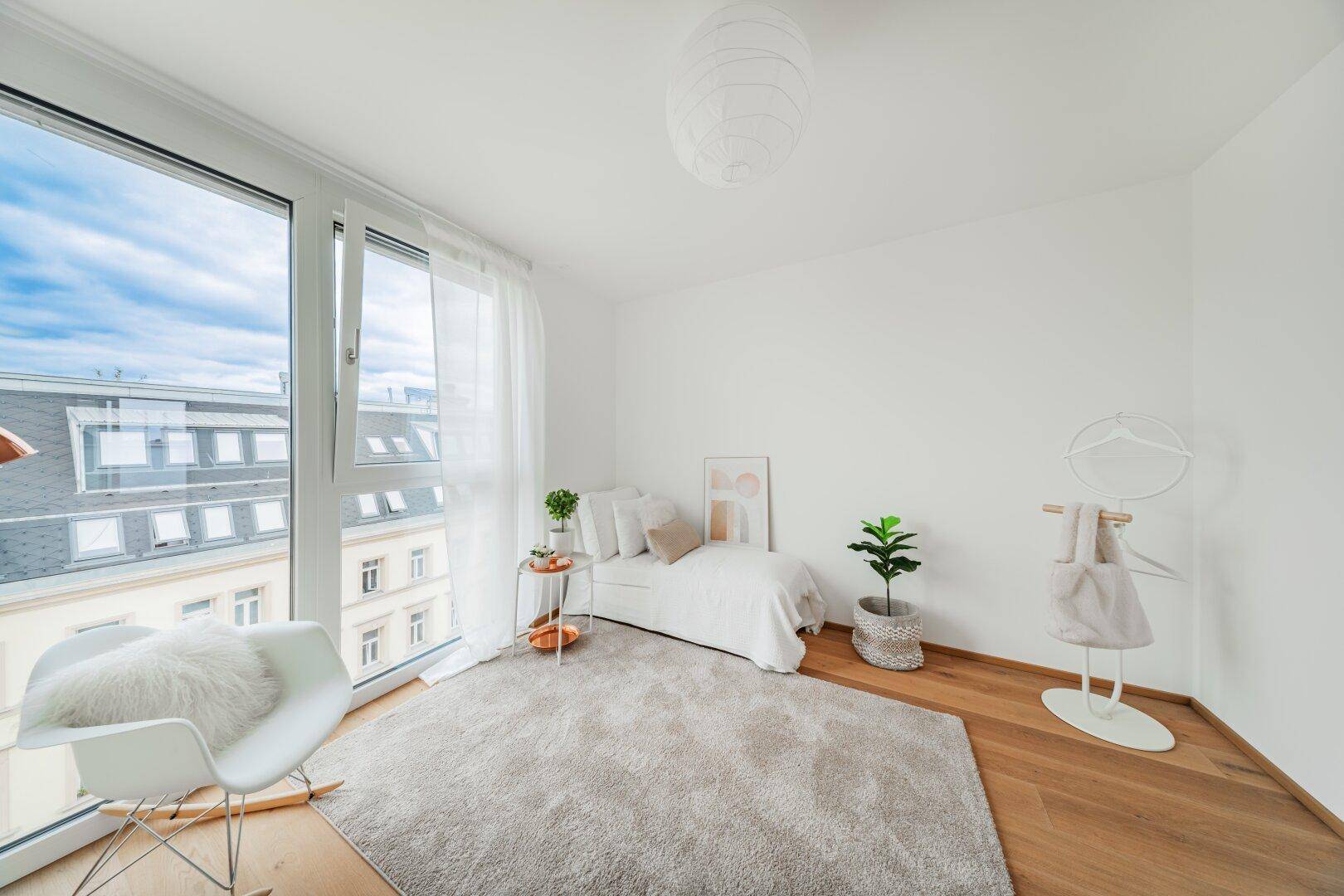 Schlafzimmer mit Holzboden, großem Fenster und Blick auf die umliegenden Gebäude.