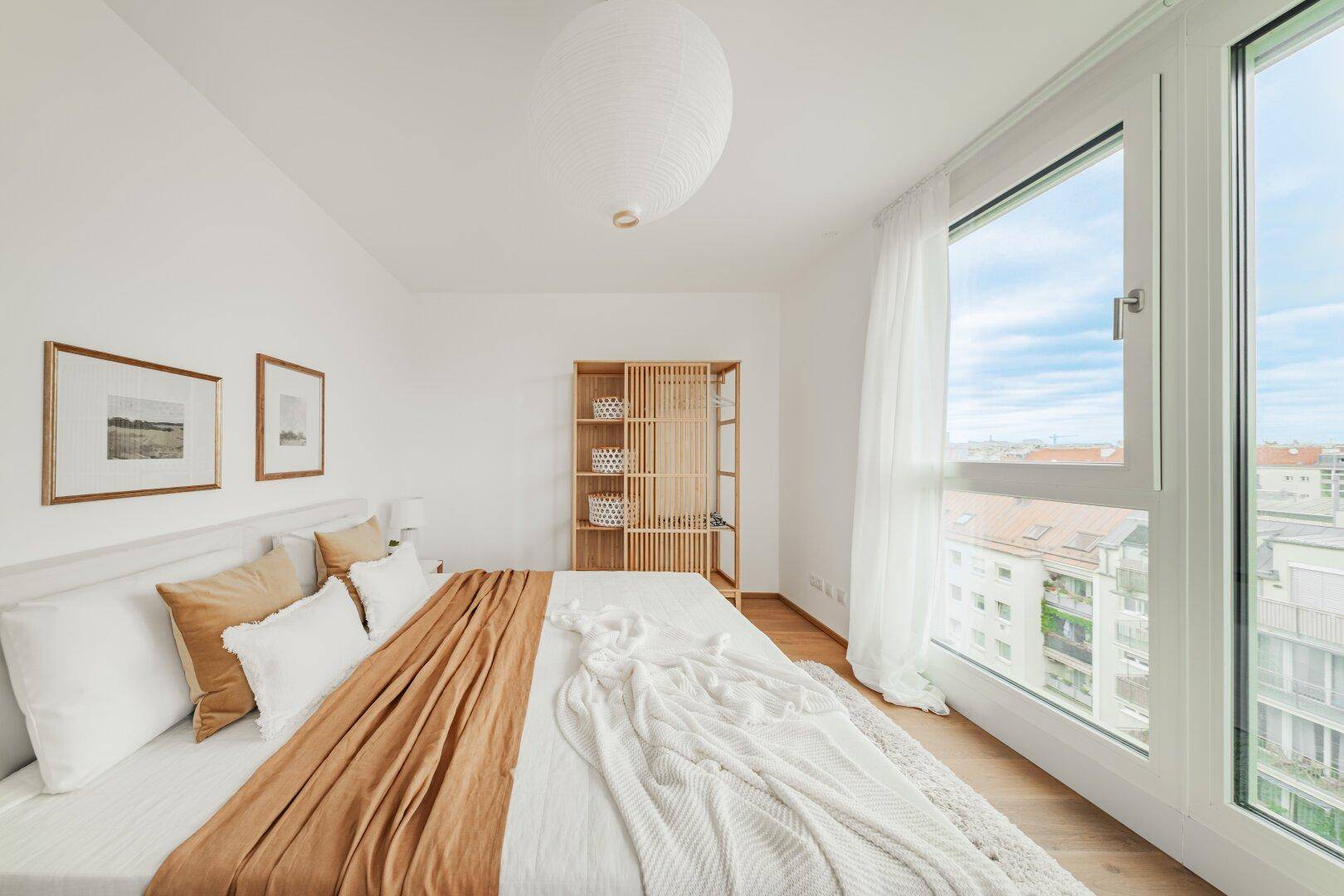 Schlafzimmer mit Holzboden, großen Fenstern und minimalistischer Einrichtung.