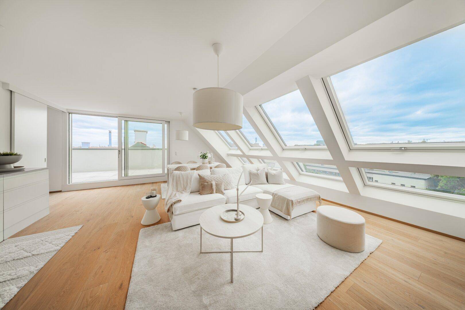 Helles Wohnzimmer mit Dachschrägenfenstern, Holzboden und Zugang zur Terrasse.