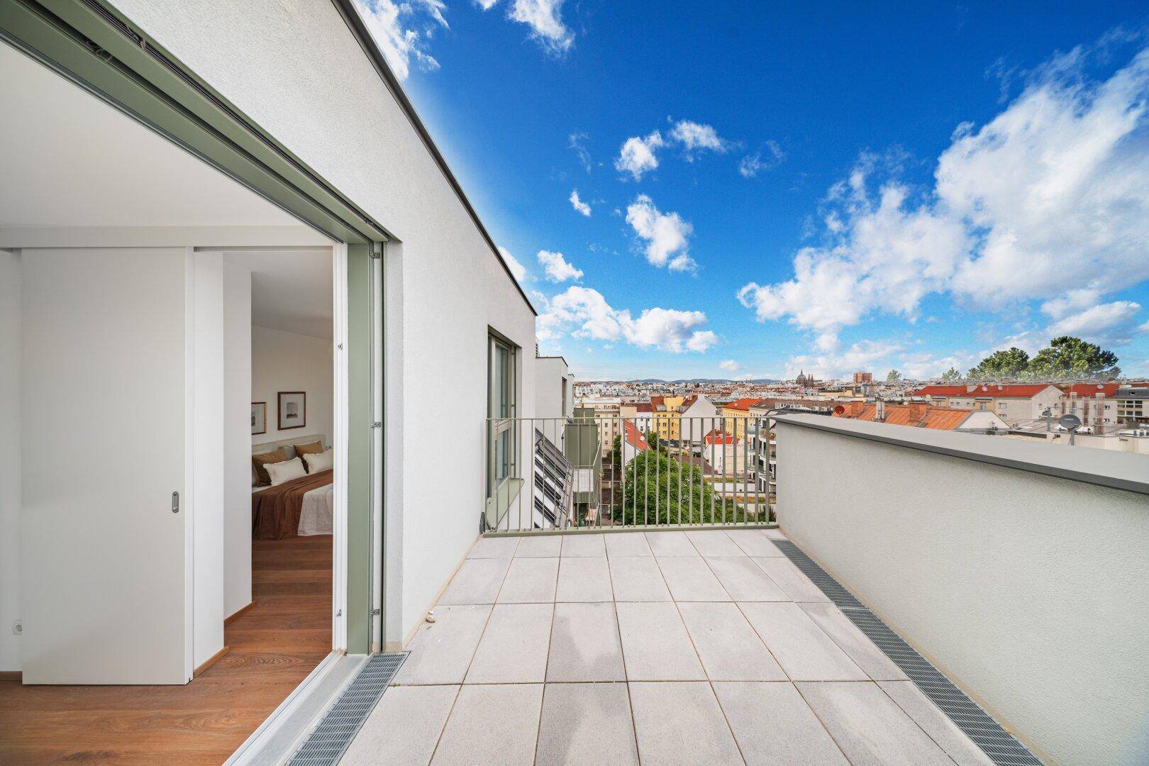 Heller Balkon mit Fliesenboden und Blick auf die Stadt und angrenzende Gebäude.
