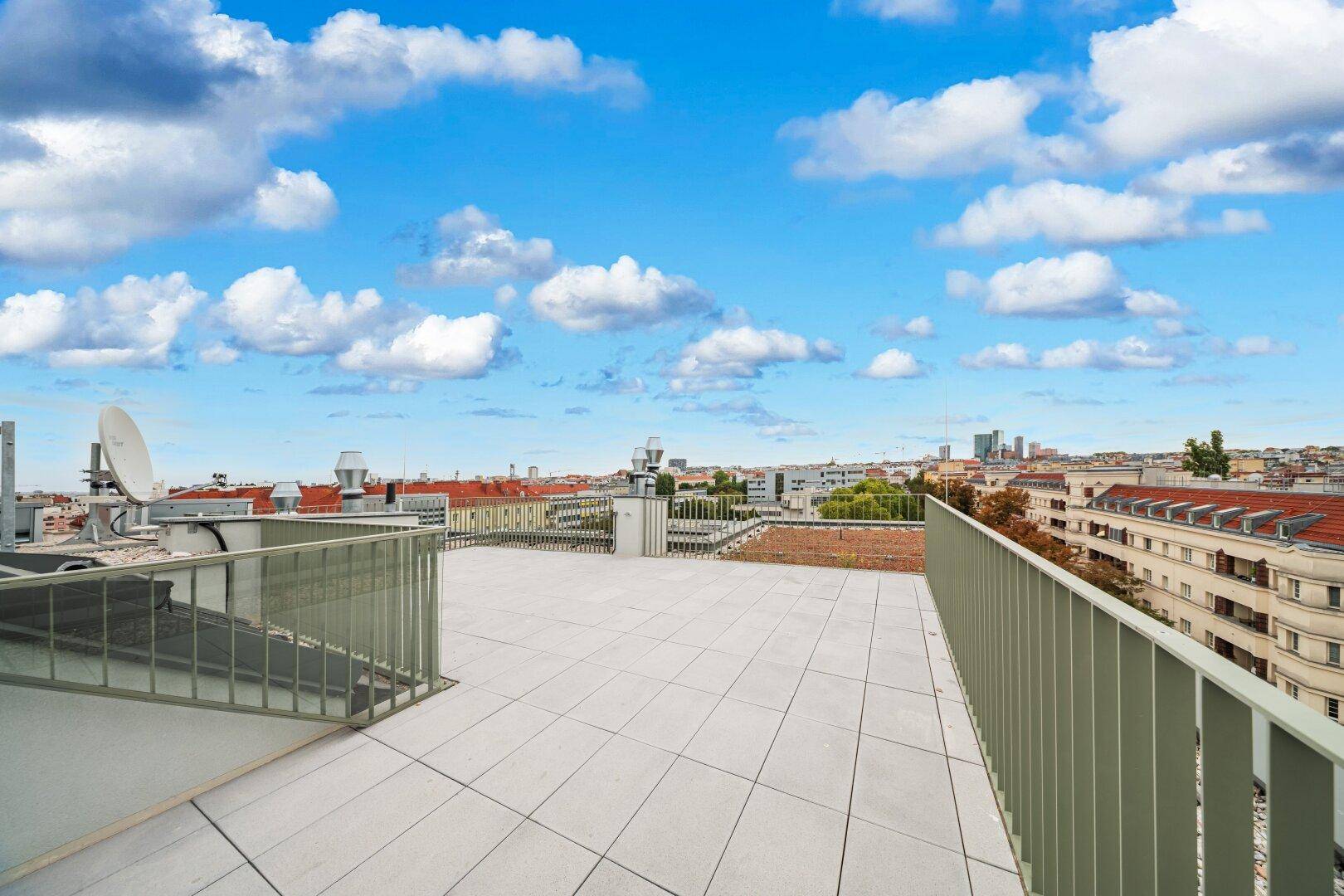 Weitläufige Dachterrasse mit Fliesenboden und Panoramablick über die Stadt.
