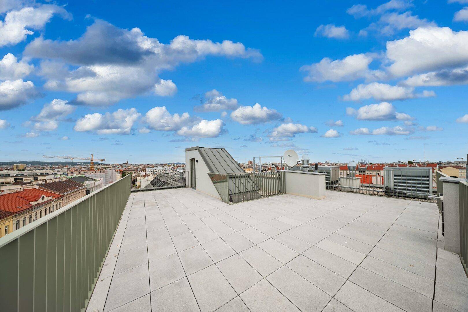 Geräumige Dachterrasse mit Fliesenboden und weitem Blick über die Stadt.