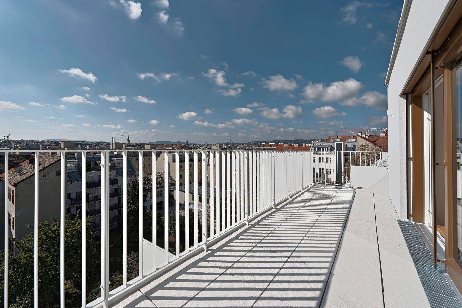 Geräumiger Balkon mit Fliesenboden und weitem Blick über die Dächer der Stadt.