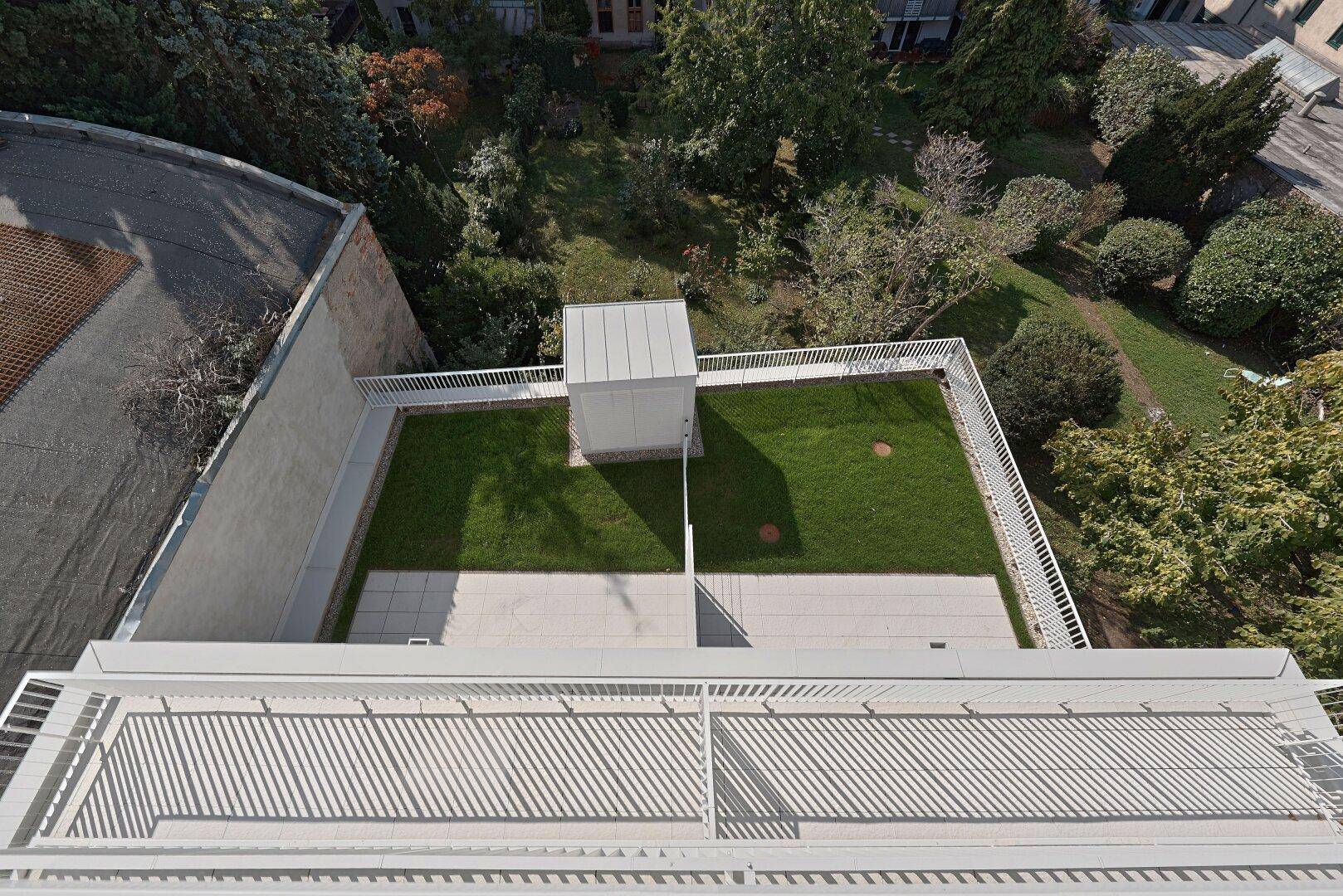 Vogelperspektive auf eine begrünte Dachfläche mit Rasen und Terrassenbereichen.
