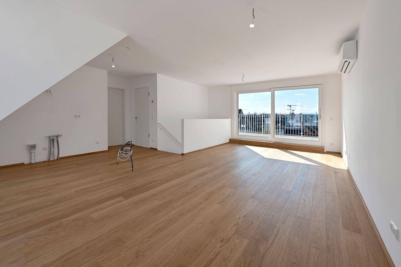 Großer, heller Raum mit Holzboden, Klimaanlage und Blick auf die Stadt.