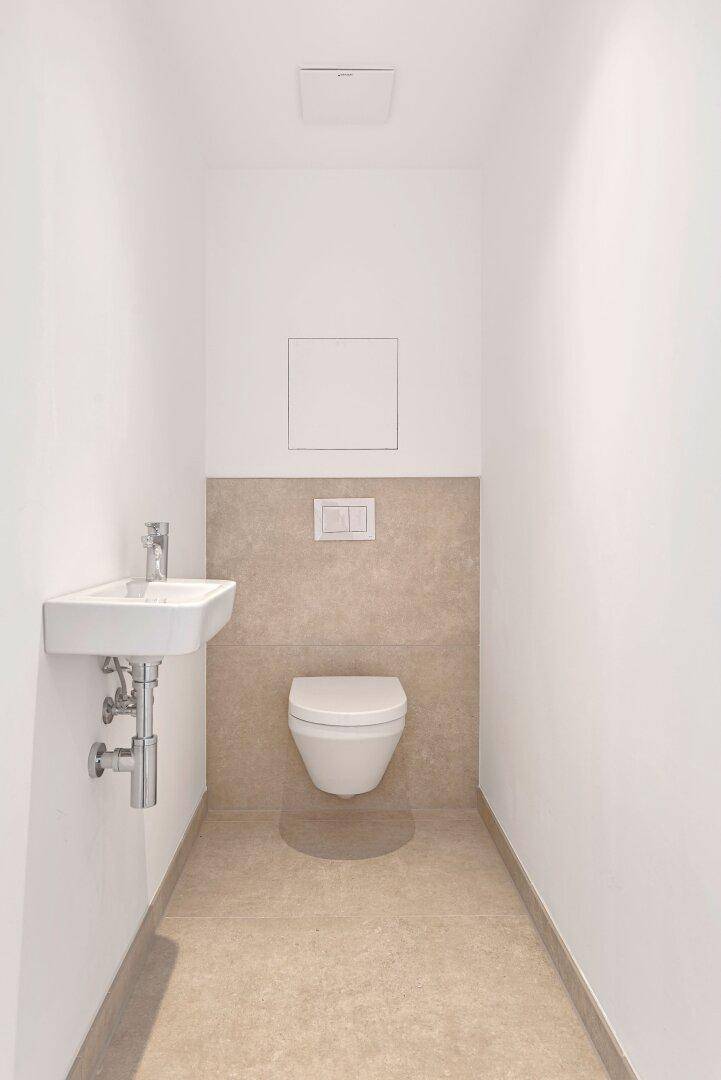 Kleines Gäste-WC mit wandhängender Toilette und kompaktem Waschbecken.
