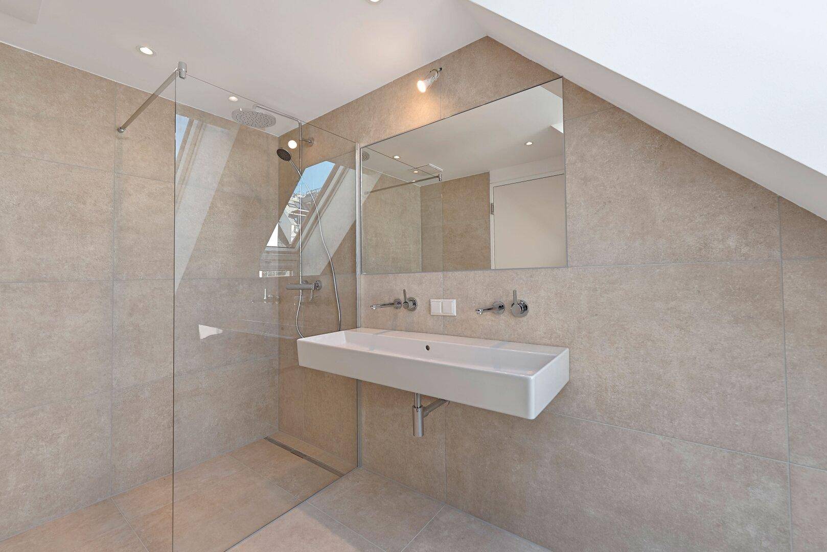 Elegantes Badezimmer mit großer begehbarer Dusche, Waschtisch und großem Spiegel.