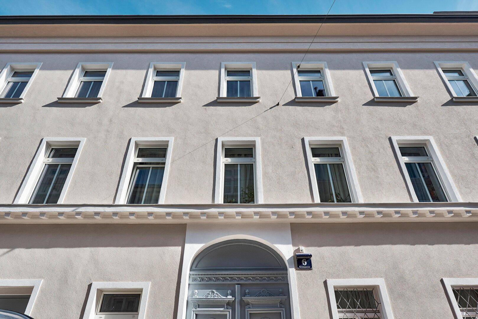 Historische Fassade eines Altbaus mit zahlreichen Fenstern und einem verzierten Eingangsbereich.