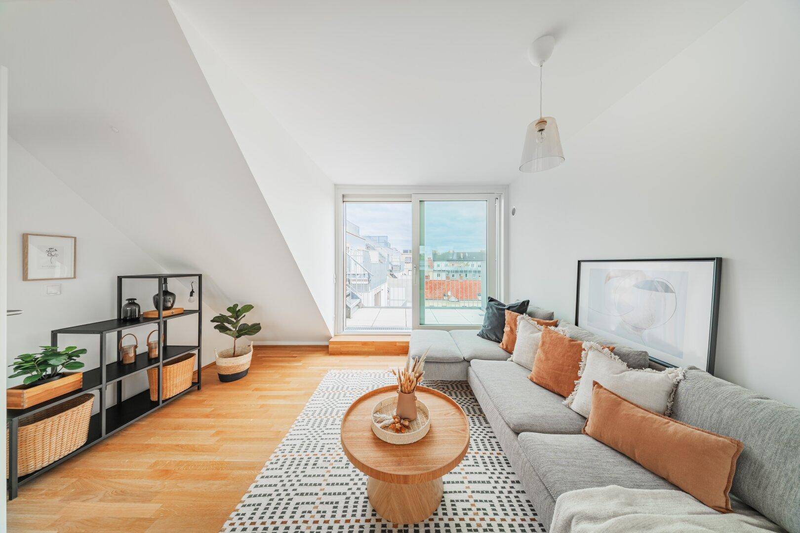 Gemütliches Wohnzimmer mit Holzboden, Dachschräge und großem Fenster mit Terrassenzugang.