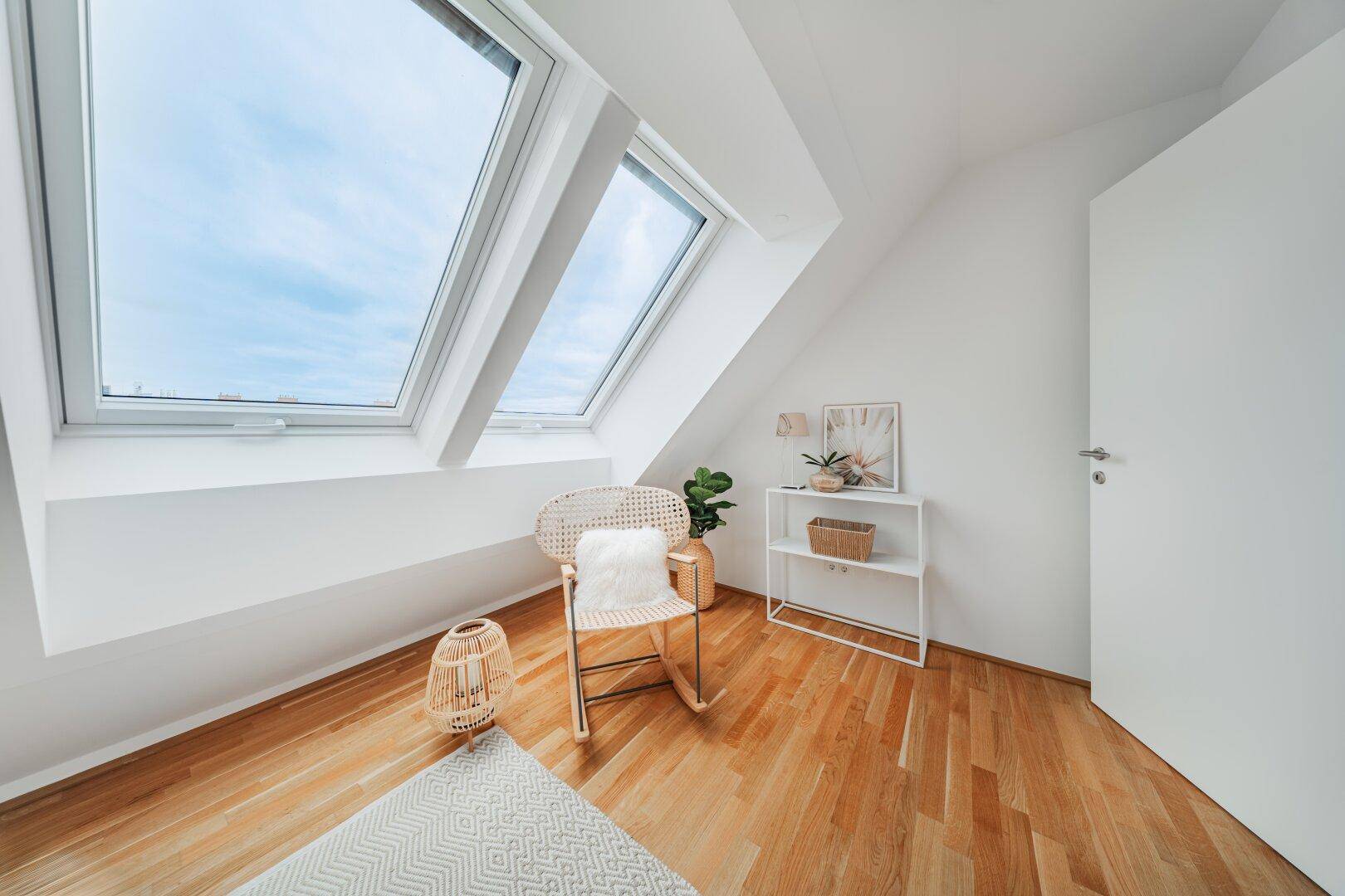 Lichtdurchflutetes Arbeitszimmer mit Holzboden, Dachschräge und zwei großen Dachfenstern.