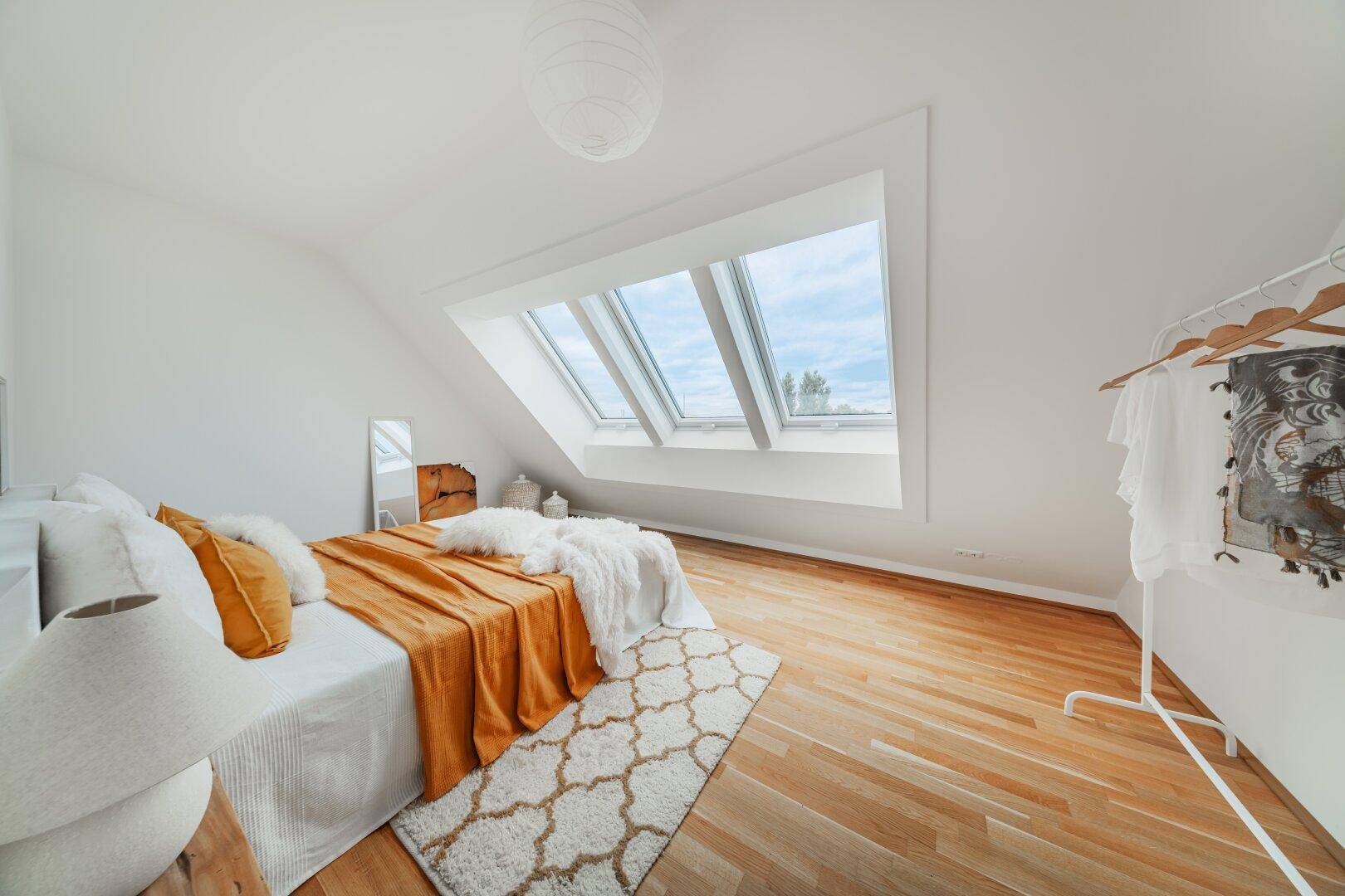 Gemütliches Schlafzimmer mit Holzboden, Dachschräge und hellen Dachfenstern.