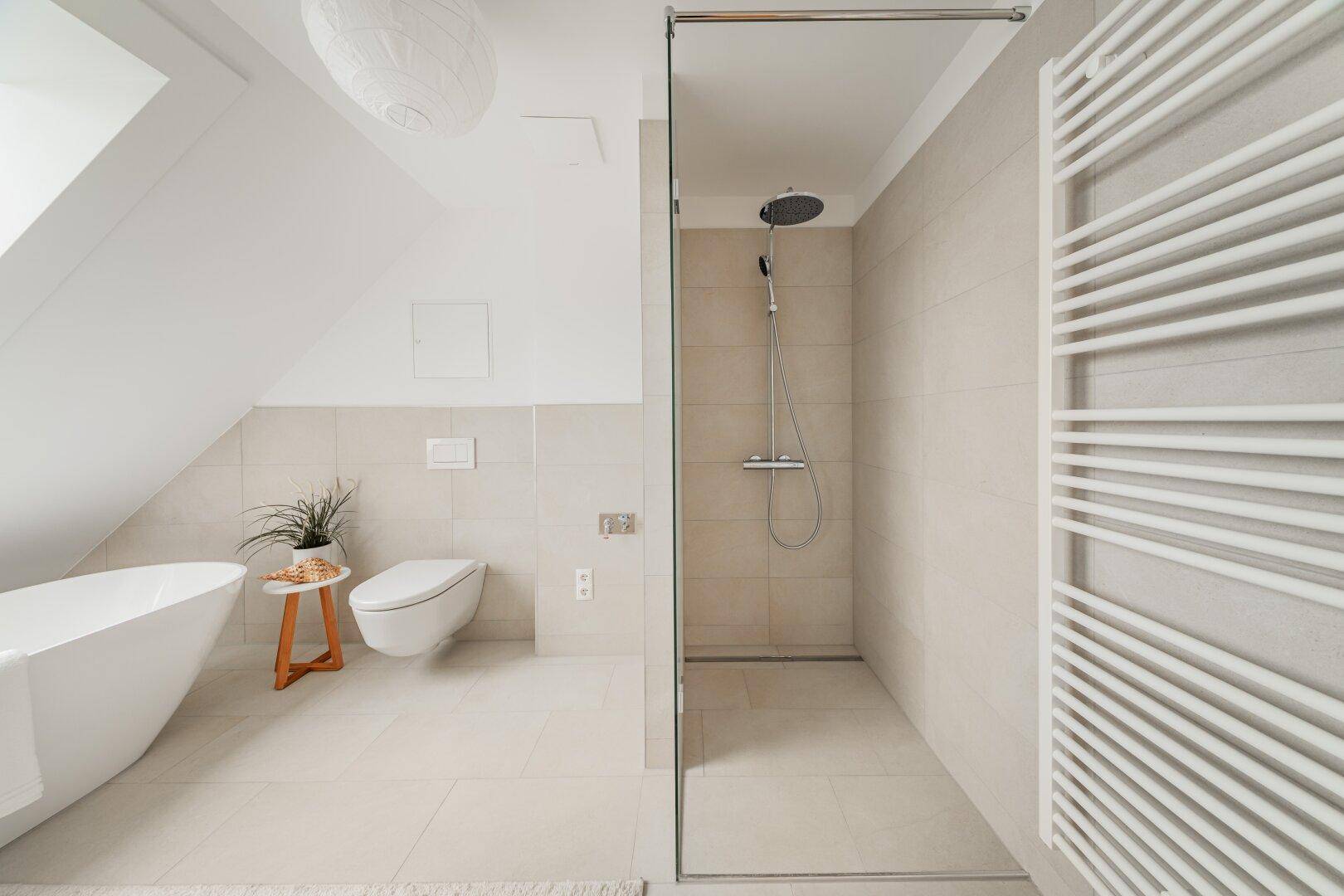Modernes Badezimmer mit freistehender Badewanne, begehbarer Dusche und beheiztem Handtuchhalter.