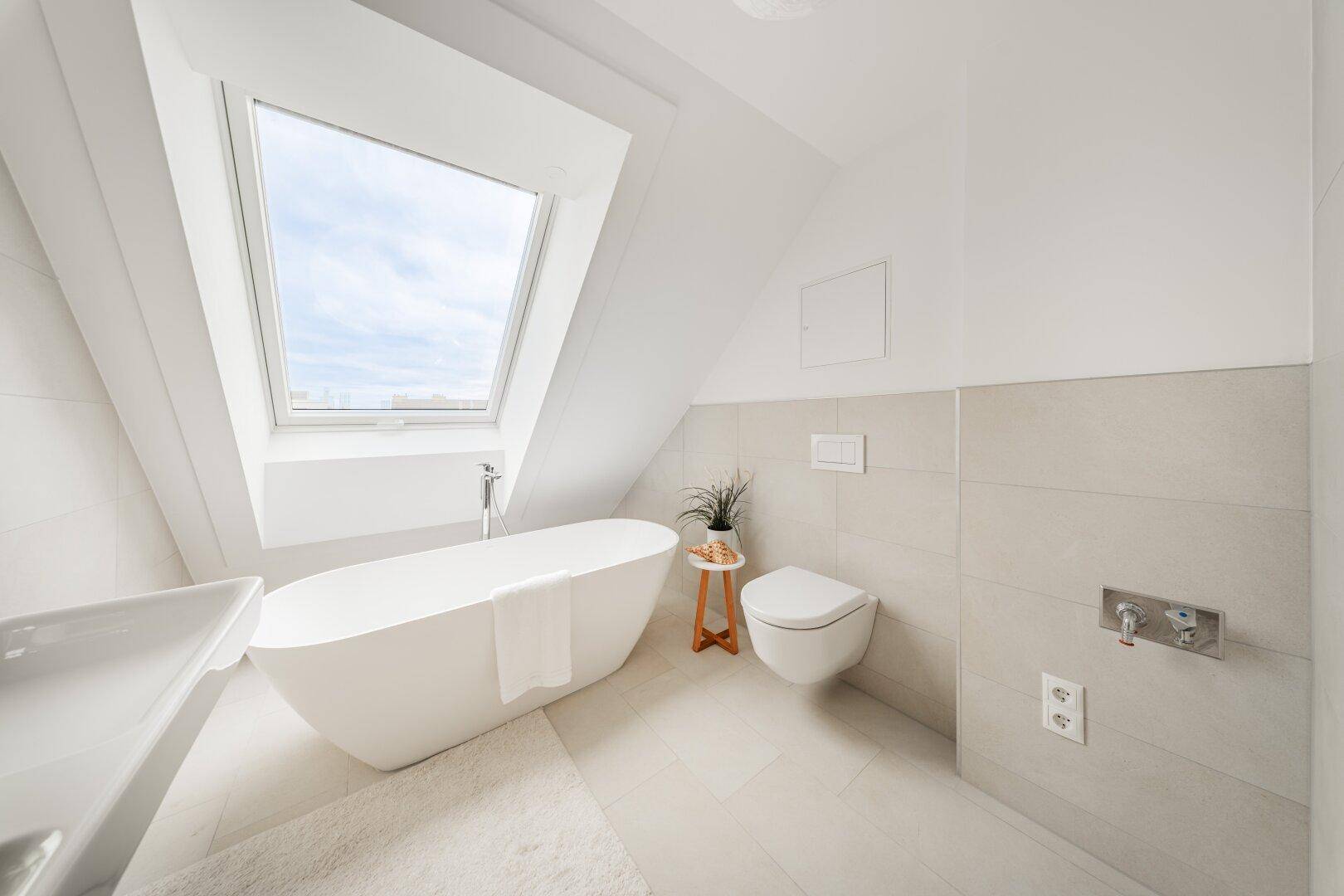 Helles modernes Badezimmer mit freistehender Badewanne, Wand-WC und Dachfenster.