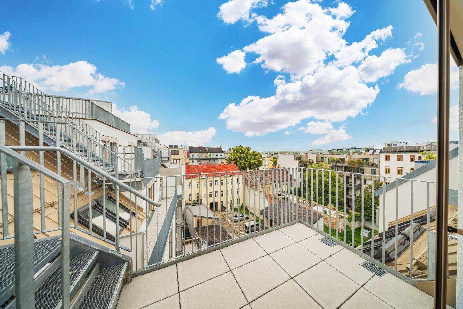 Geräumige Dachterrasse mit Metallgeländer und weitem Blick über die Stadt.