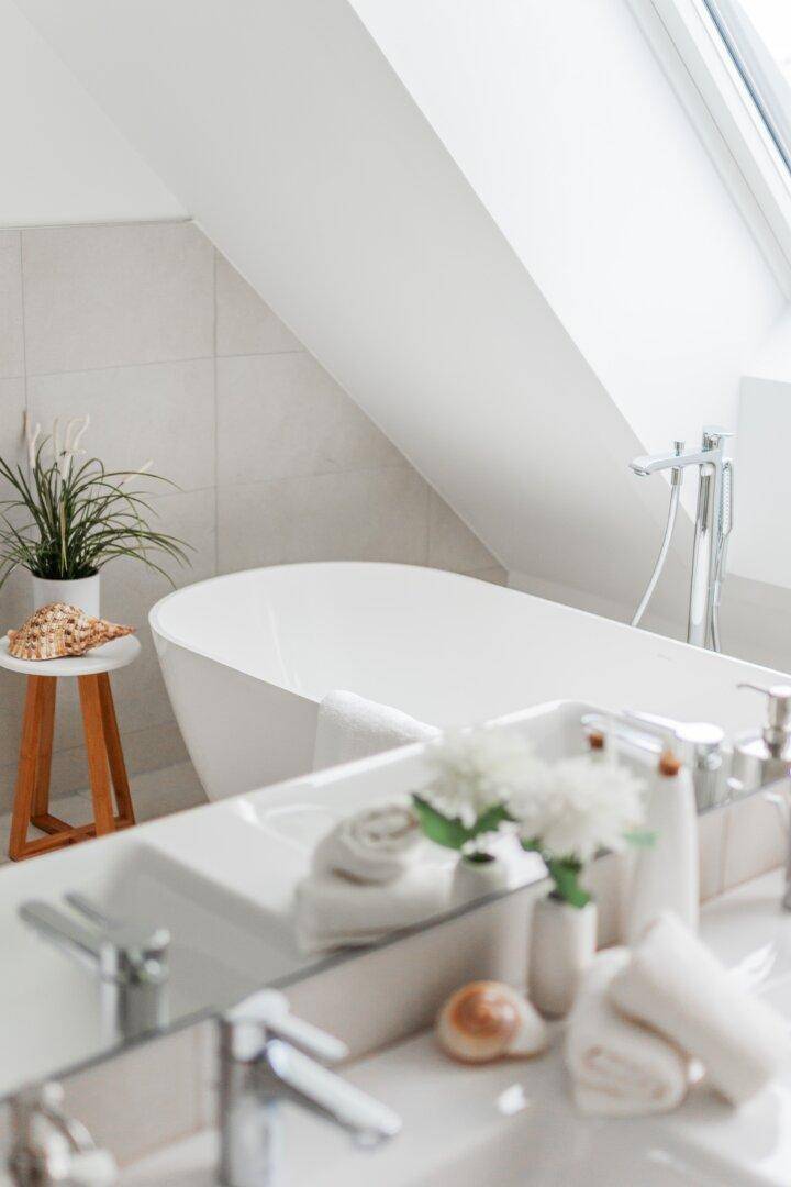 Freistehende Badewanne und Doppelwaschbecken in einem modernen Badezimmer mit Tageslicht.
