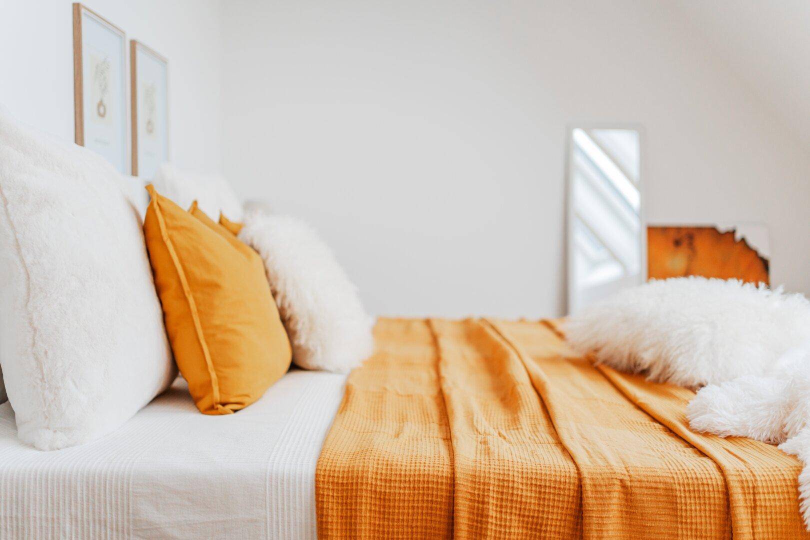 Nahaufnahme eines Bettes mit farbigen Kissen und Decken in einem Schlafzimmer.