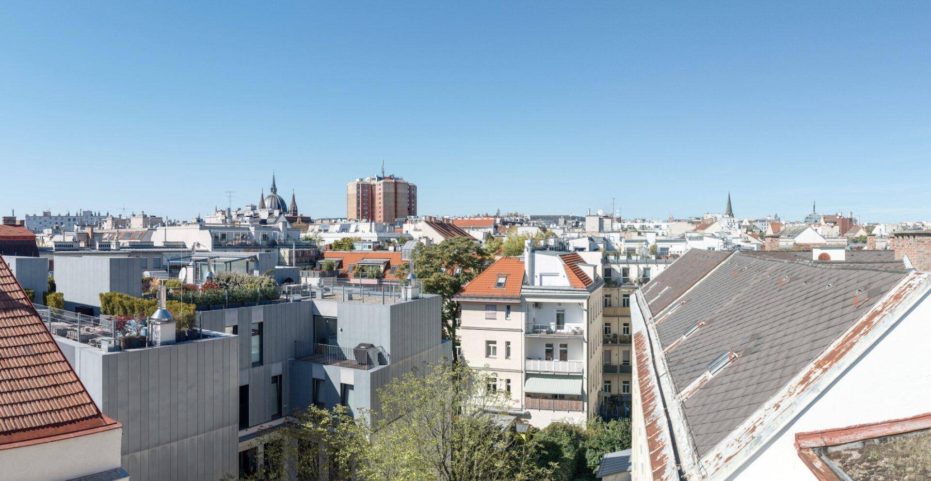Panoramablick über die Dächer einer Stadt mit blauem Himmel an einem sonnigen Tag.