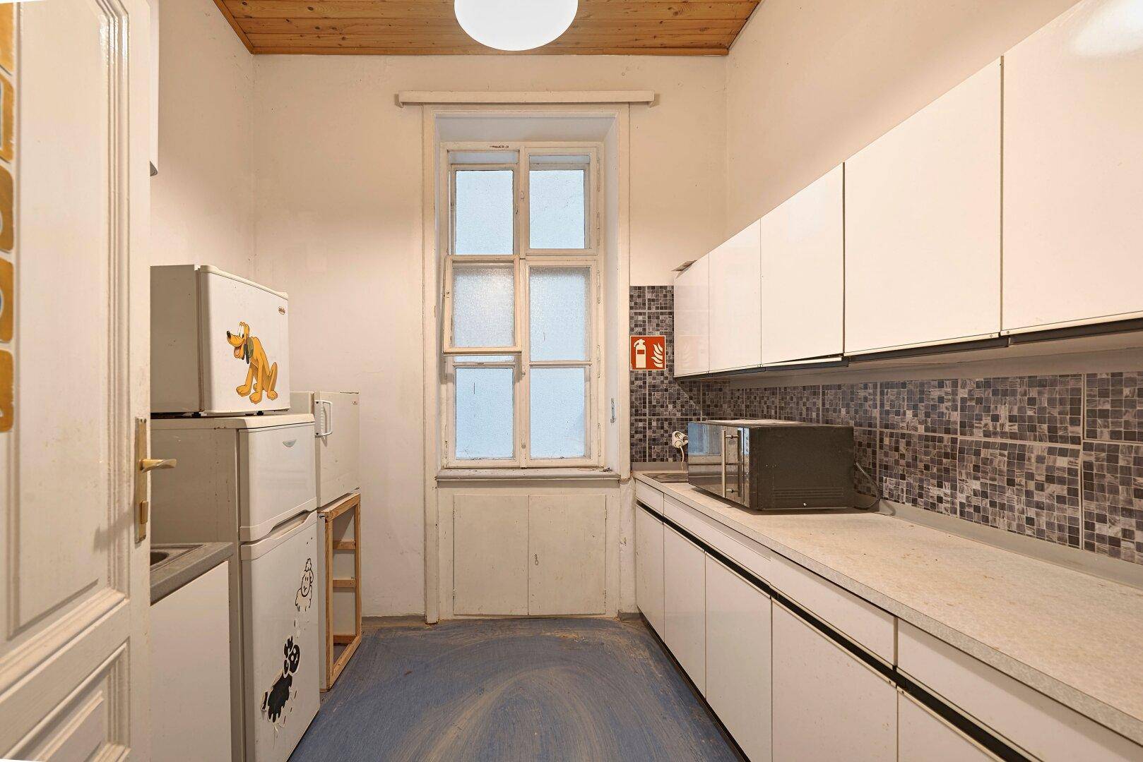Kleine Küche mit weißen Schränken, Mosaikfliesen, Holzdecke und einem Fenster für natürliches Licht.