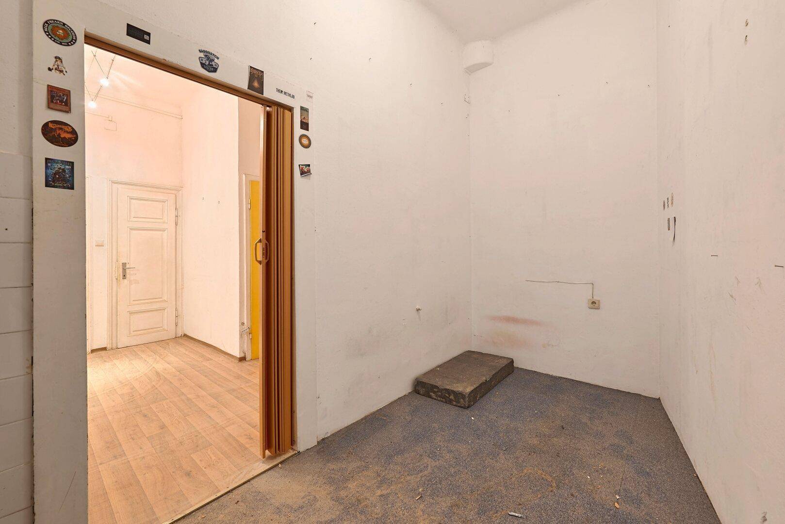 Leerer Raum mit Teppichboden und einem Durchgang zu einem angrenzenden Zimmer mit Laminat.