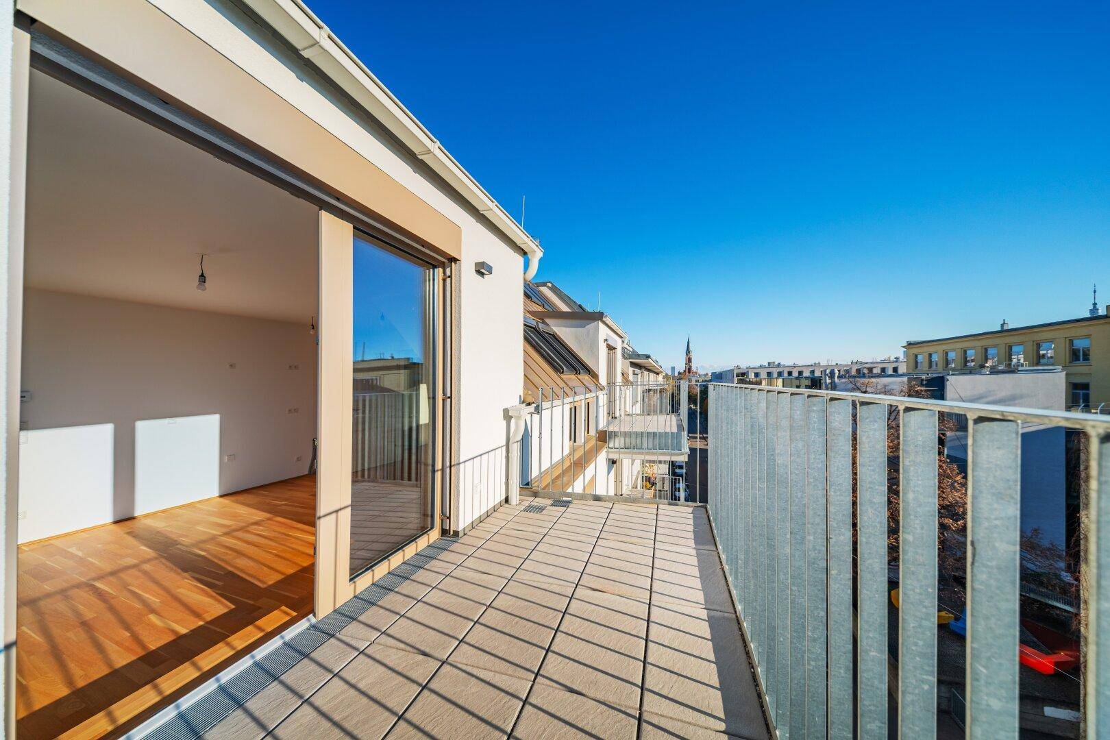 Breite Dachterrasse mit Zugang zum Innenbereich und Panoramablick über die Stadt.