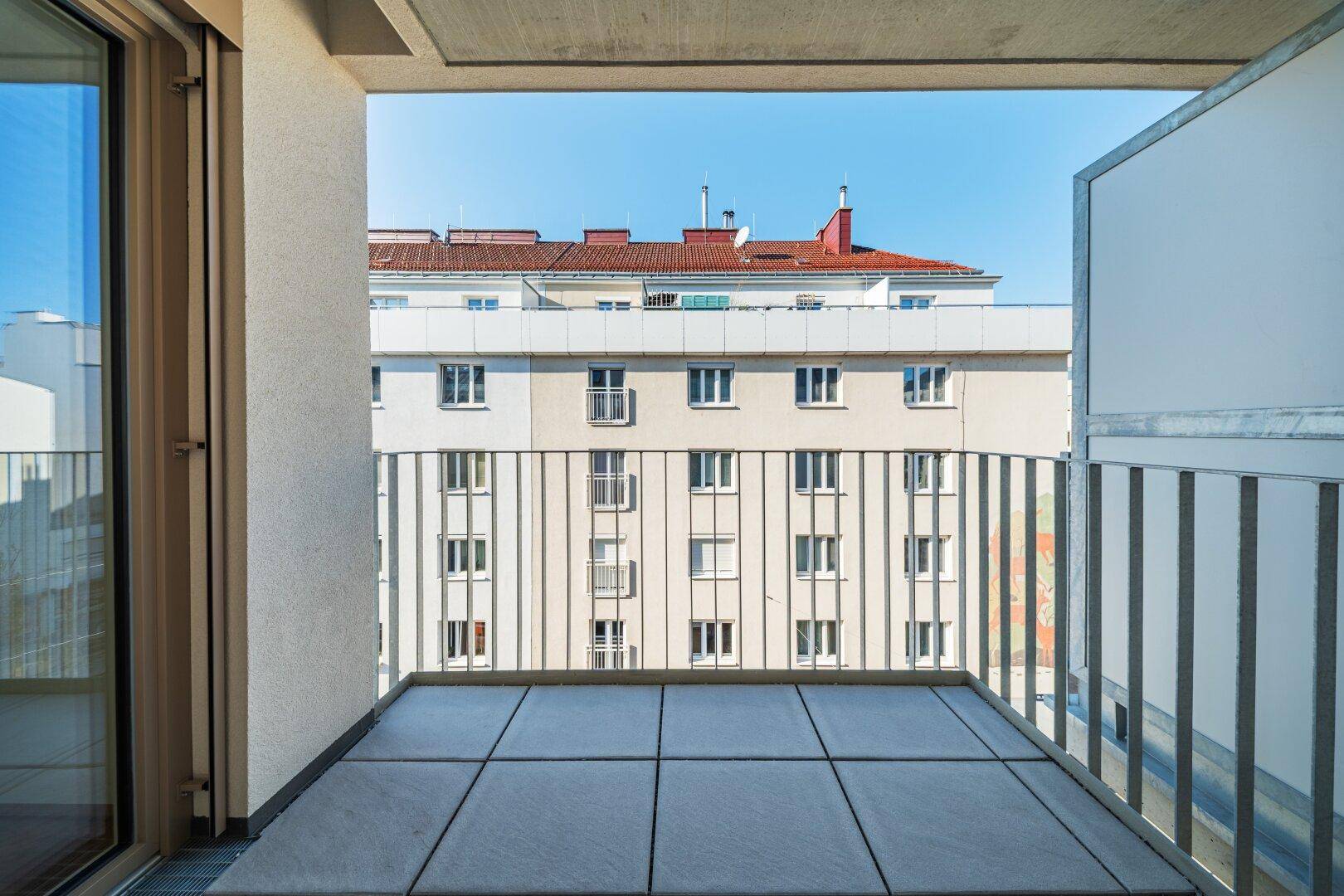 Geräumiger Balkon mit Fliesenboden und Blick auf die umliegenden Gebäude der Stadt.
