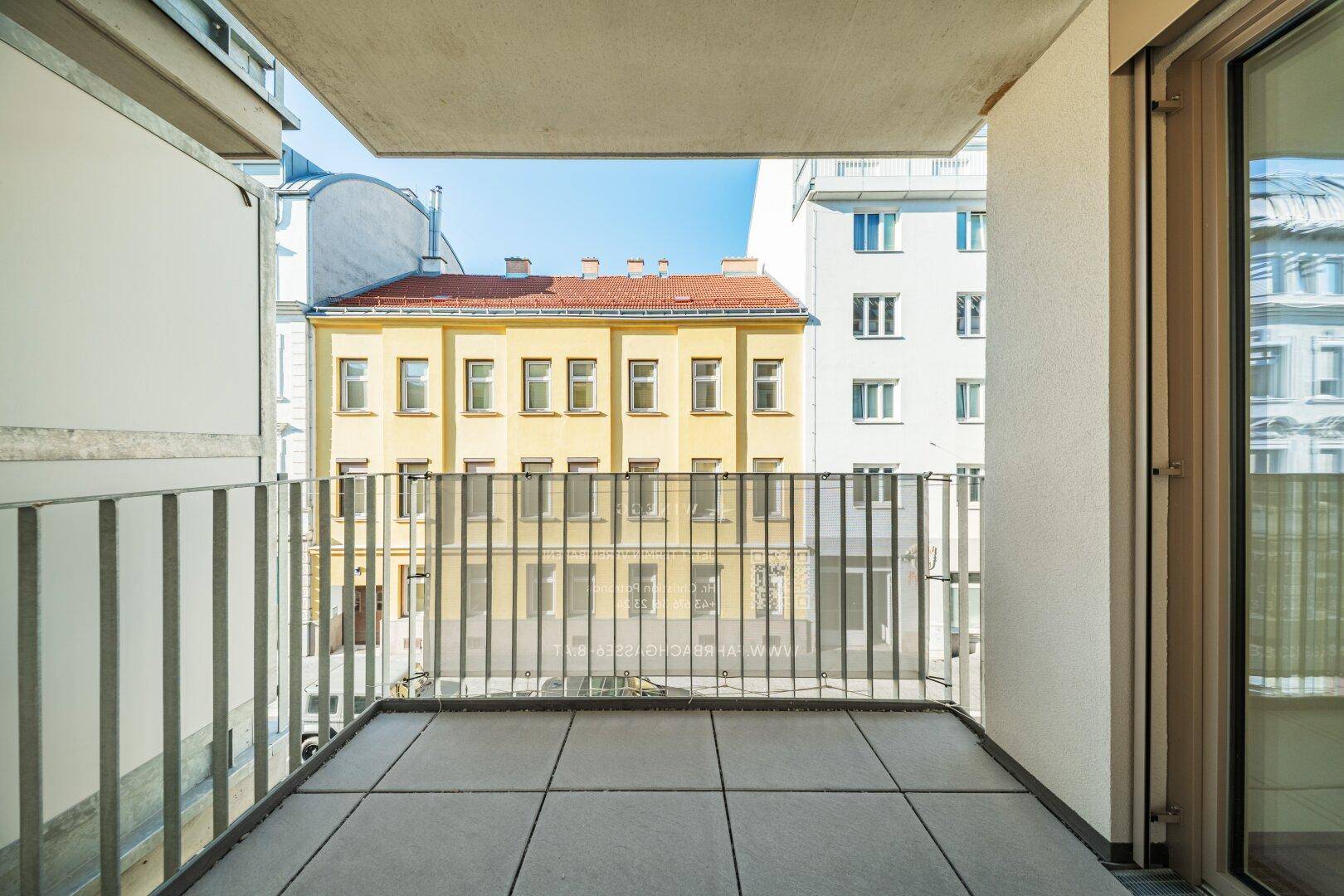 Kleiner Balkon mit Fliesenboden und Blick auf die umliegenden Gebäude der Stadt.