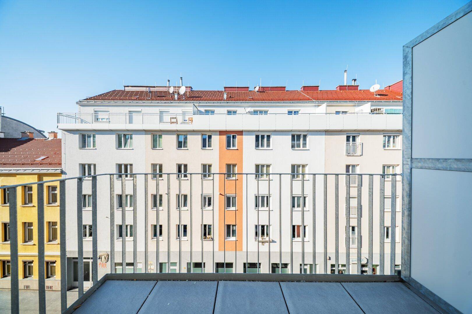 Blick vom Balkon auf die gegenüberliegende Wohnbebauung mit verschiedenen Fassaden.