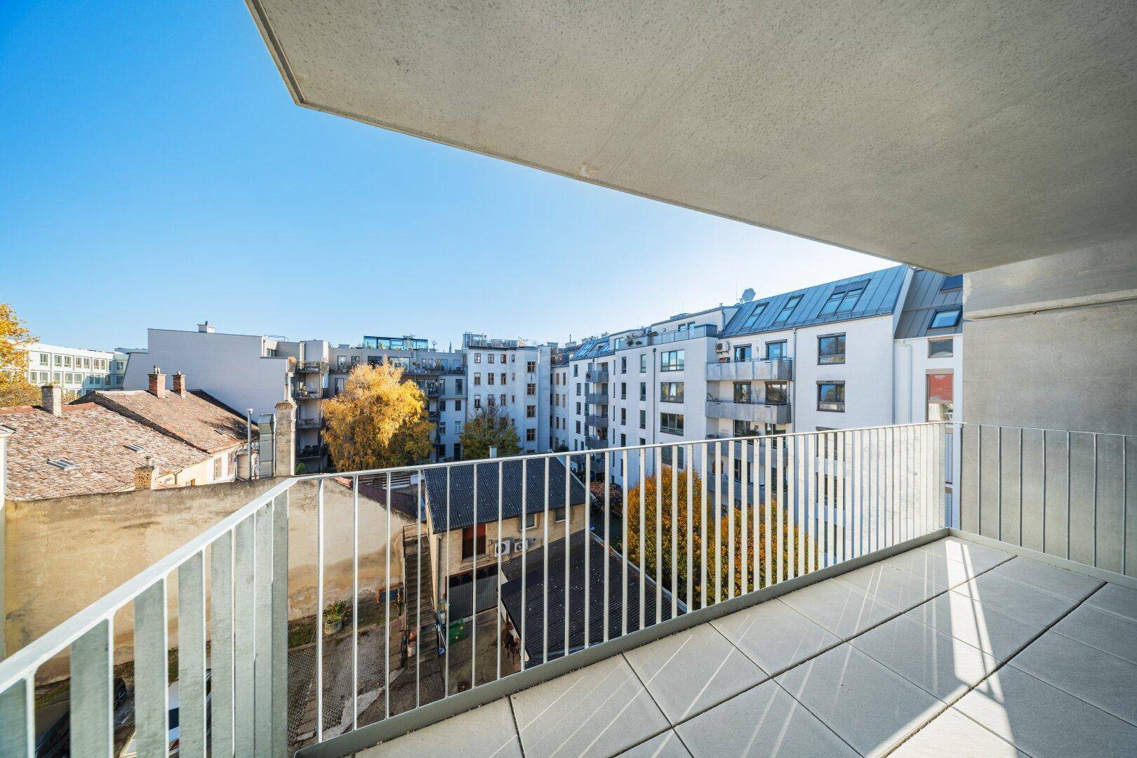 Geräumiger Balkon mit Fliesenboden und Blick auf die umliegenden Gebäude.