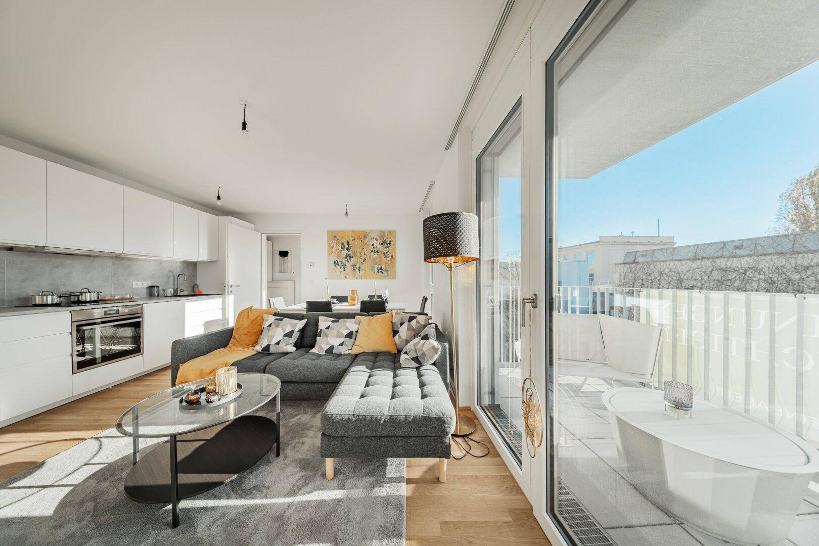 Geräumiger Wohn-Essbereich mit integrierter Küche und direktem Zugang zum sonnigen Balkon.
