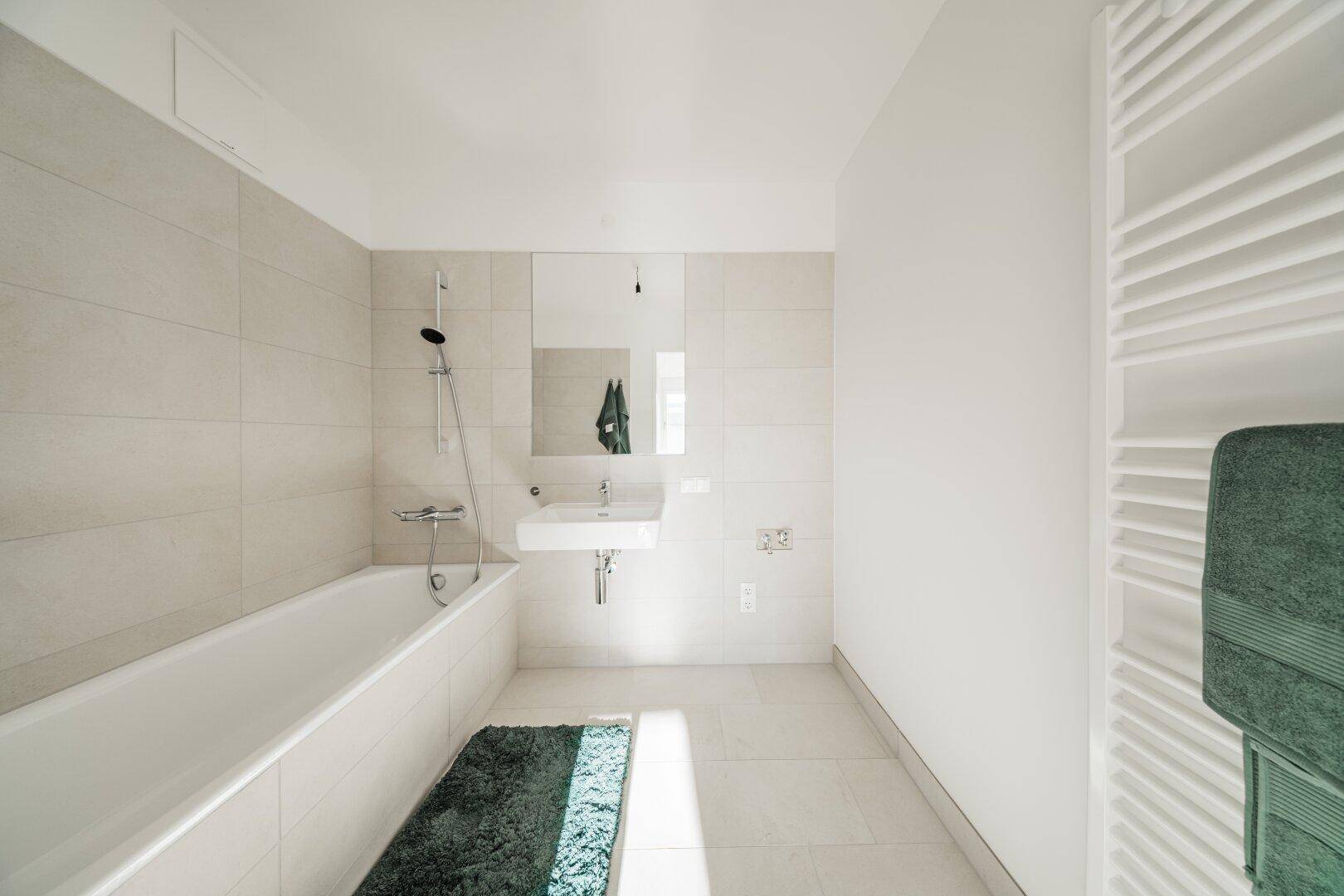 Modernes Badezimmer mit Badewanne, Wandfliesen und beheiztem Handtuchhalter.
