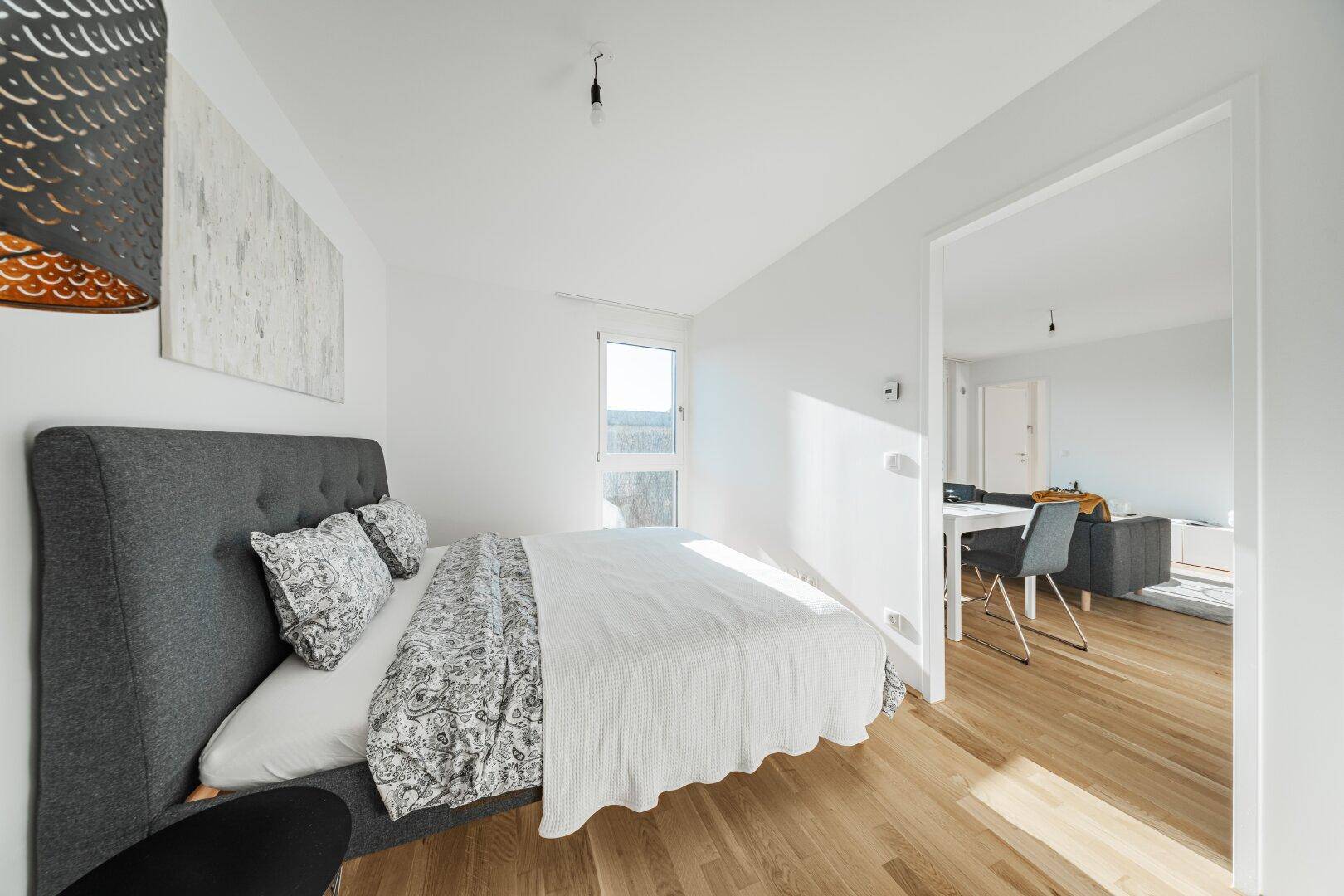 Gemütliches Schlafzimmer mit Holzboden und direktem Zugang zum offenen Wohnbereich.