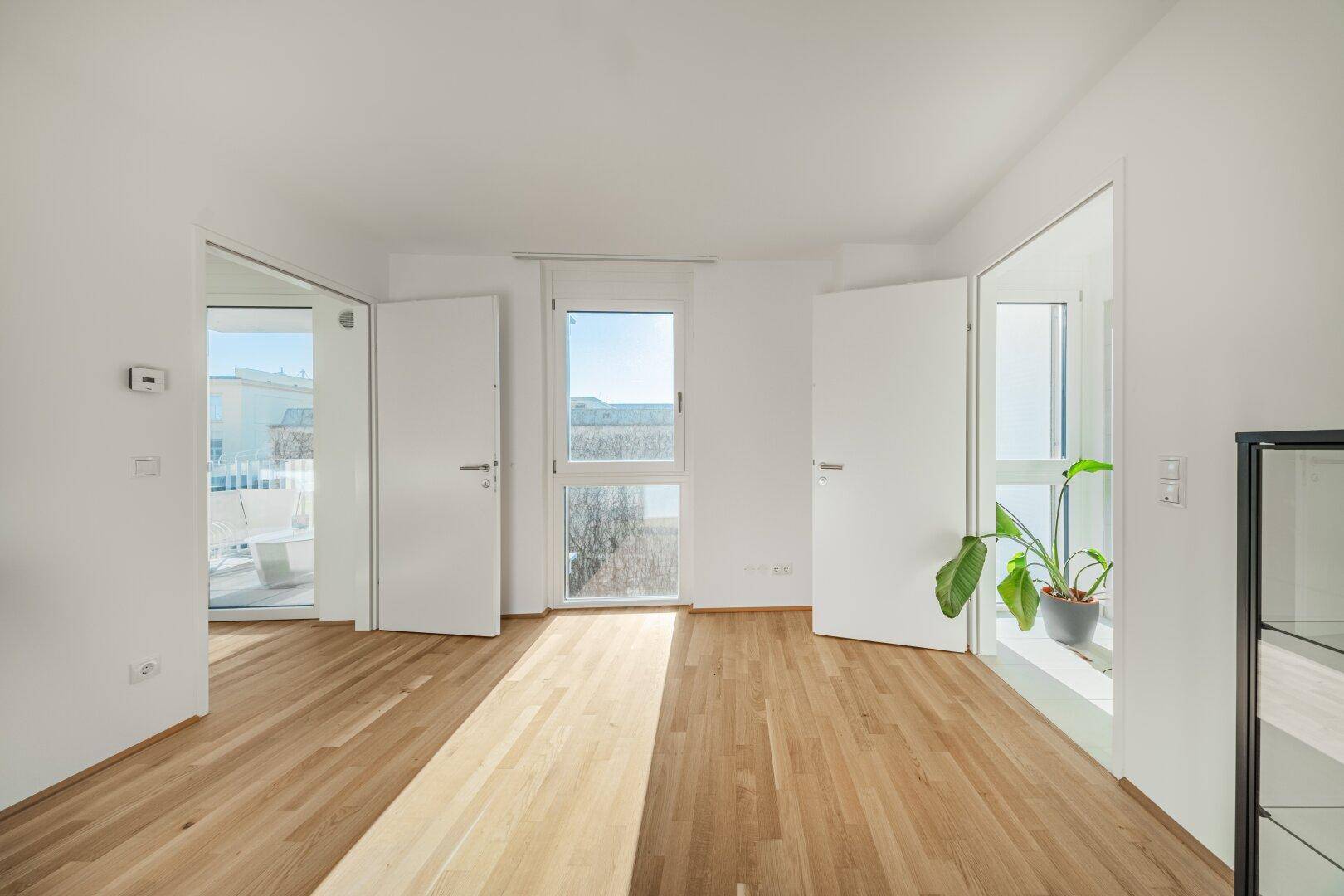Geräumiges Schlafzimmer mit Holzboden und mehreren Türen, die zu anderen Räumen führen.