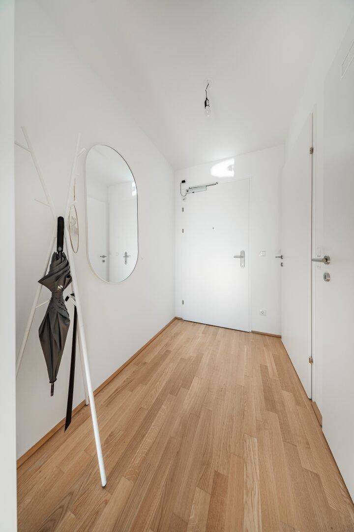 Eingangsbereich mit Holzboden, Garderobe und Zugang zu verschiedenen Räumen.