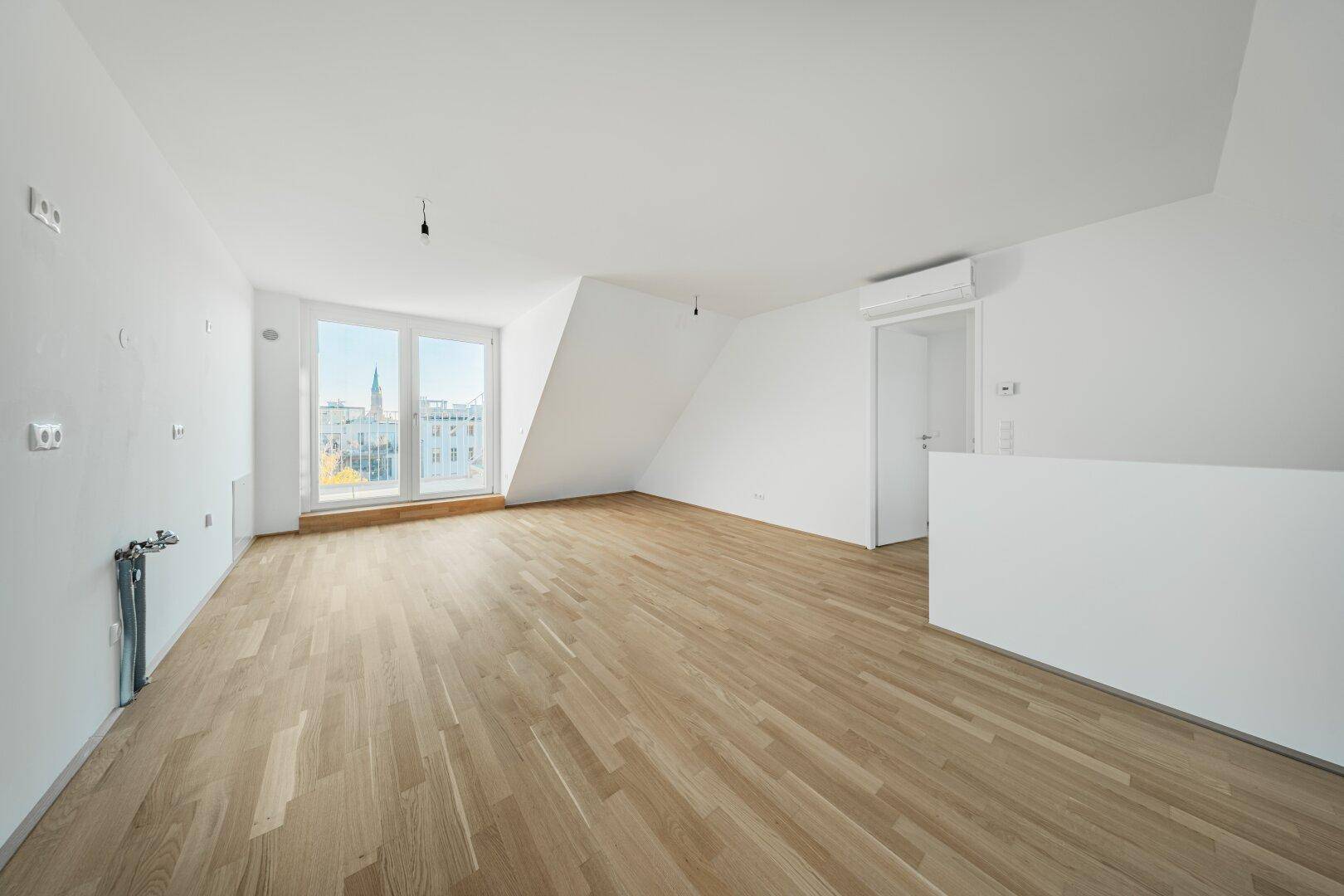 Geräumiger Wohnbereich mit Parkettboden, Klimaanlage und Zugang zu einem Balkon oder einer Terrasse.