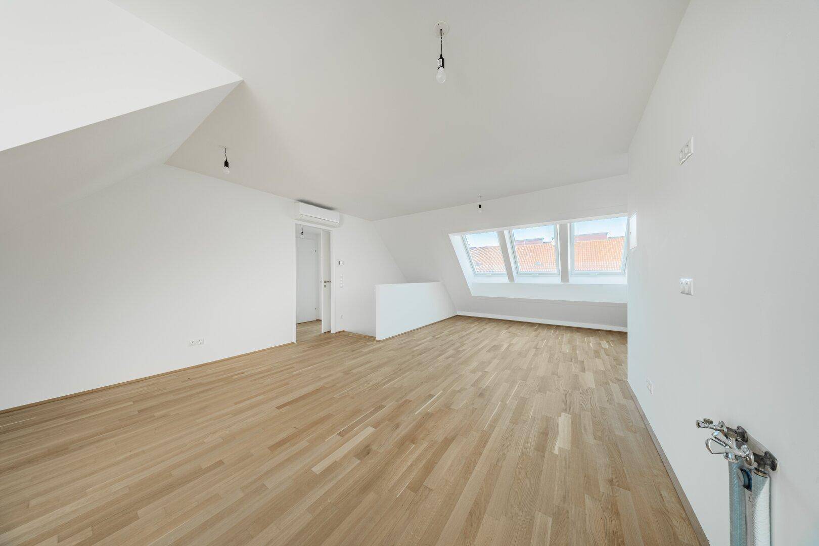 Weitläufiger Dachraum mit Parkettboden, Klimaanlage und mehreren Dachfenstern für optimale Belichtung.