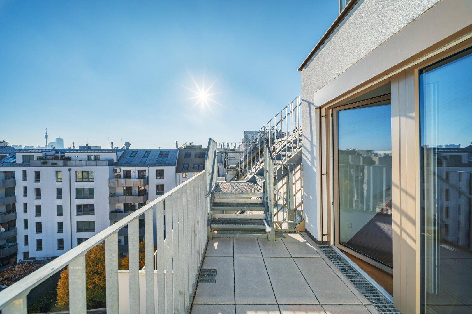 Sonnige Dachterrasse mit Stadtblick und Metallgeländer, ideal für Entspannung im Freien.
