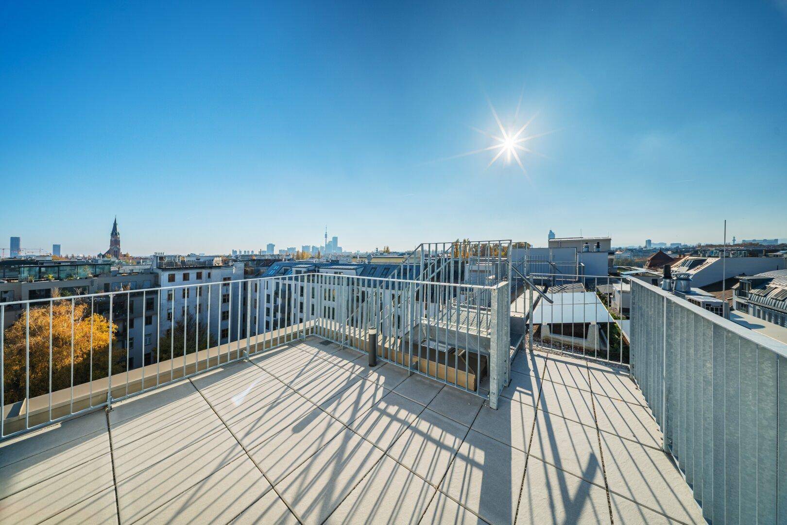 Weitläufige Dachterrasse mit Panoramablick über die Stadt unter strahlend blauem Himmel.