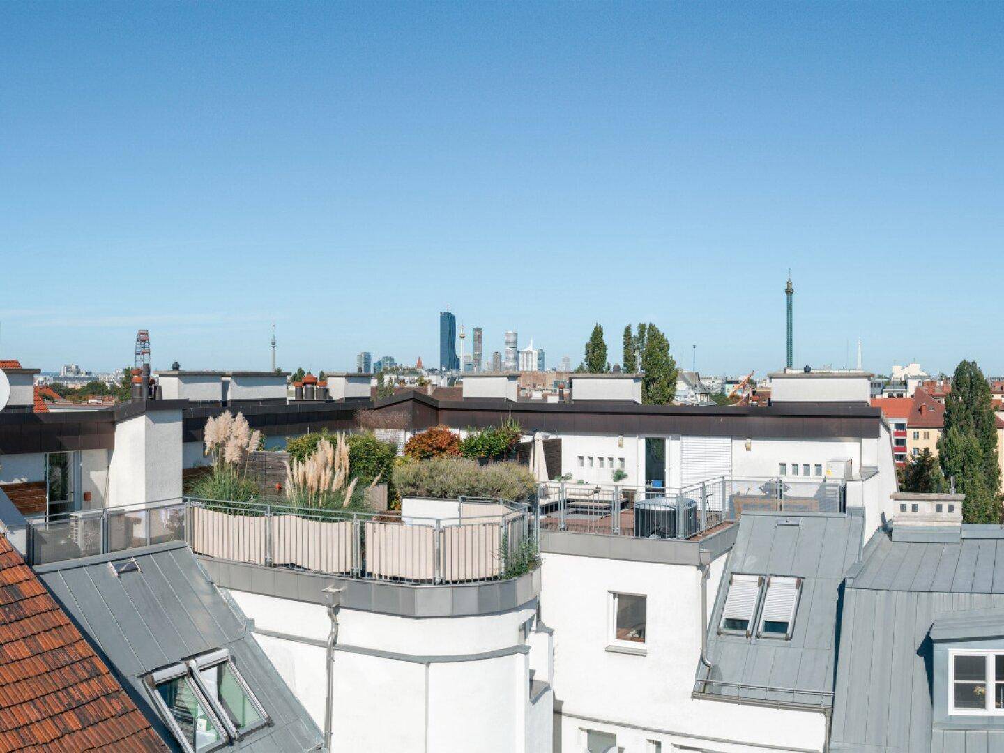 Mehrere begrünte Dachterrassen mit Sitzgelegenheiten und Panoramablick auf die Stadt.