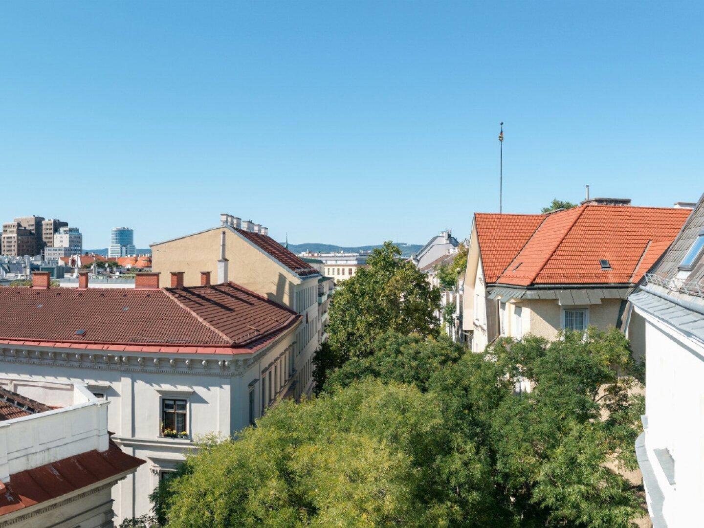 Blick über die Dächer der Stadt mit viel Grün und historischer Architektur.