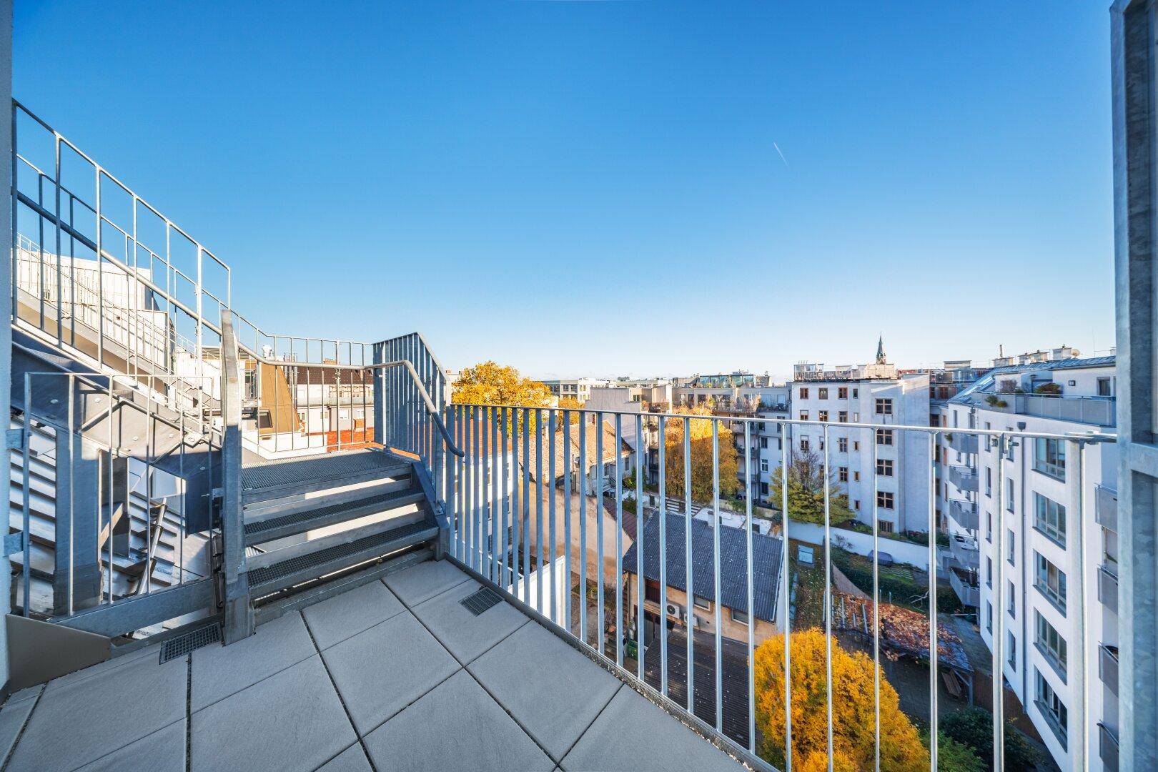 Dachterrasse mit Metallgeländer und Blick über die Stadt.