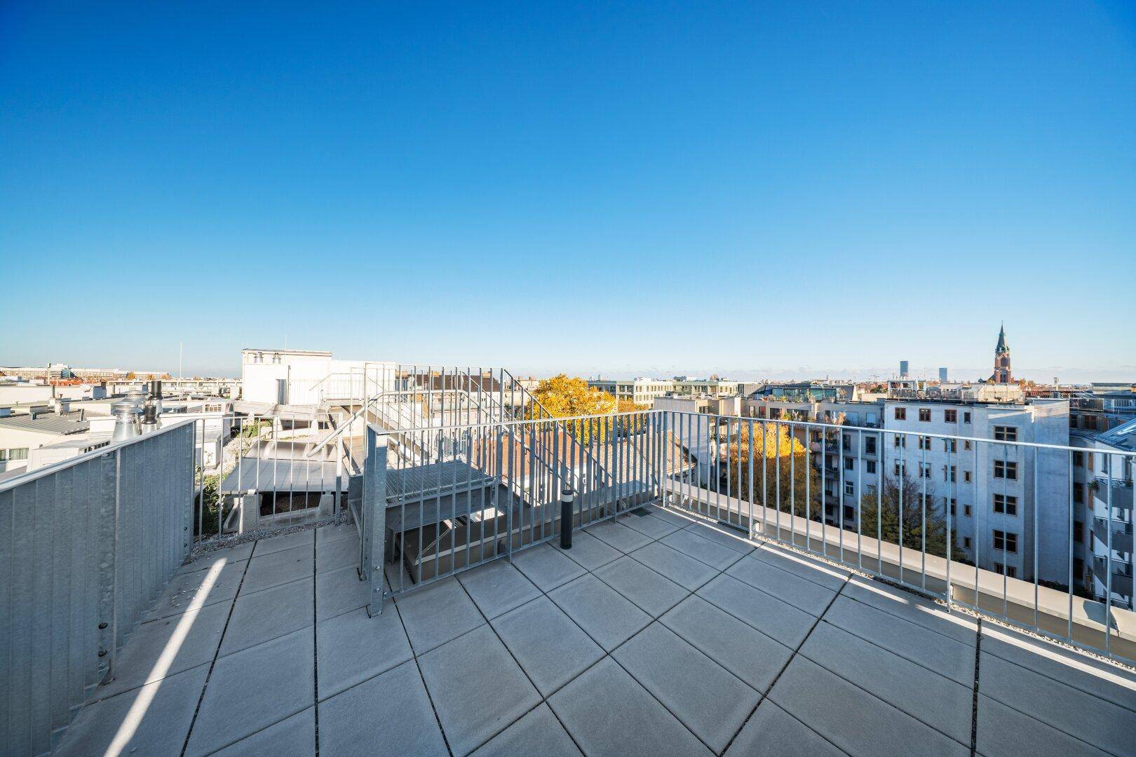 Geräumige Dachterrasse mit Fliesenboden und weitem Blick über die Stadt.