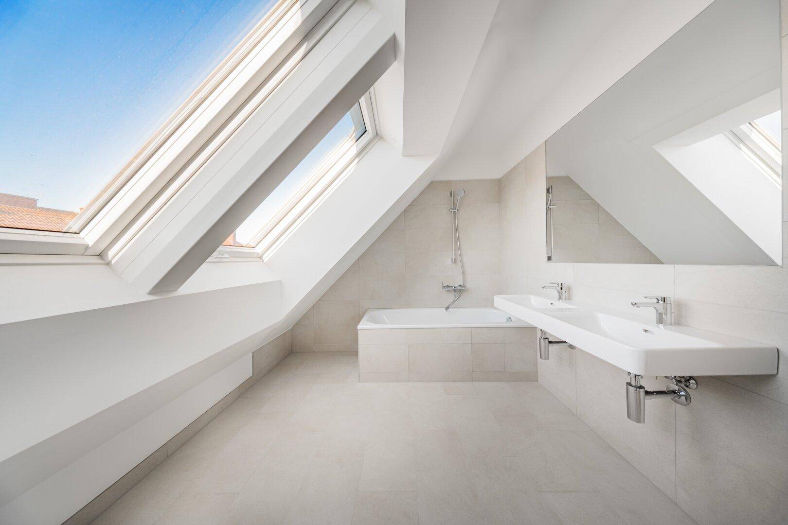 Geräumiges Badezimmer mit Doppelwaschbecken, Badewanne und Dachfenstern.
