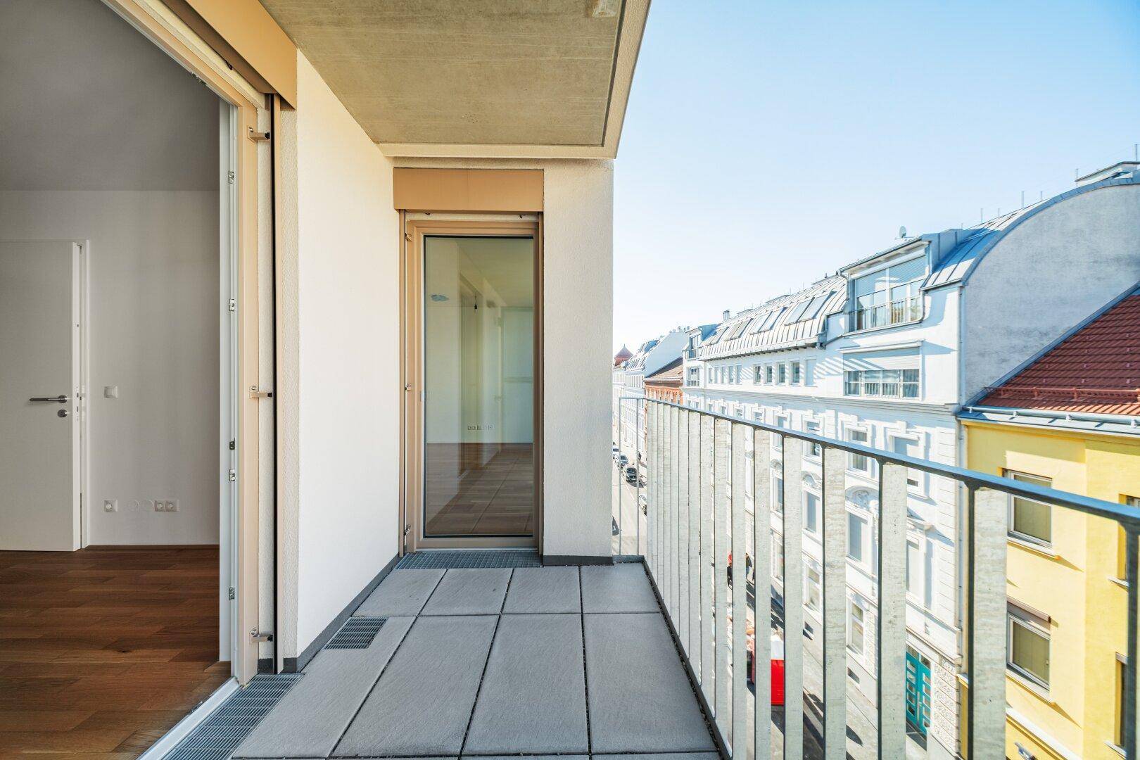 Leerer Balkon mit Fliesenboden und Metallgeländer, bietet einen weiten Blick auf die Straße.