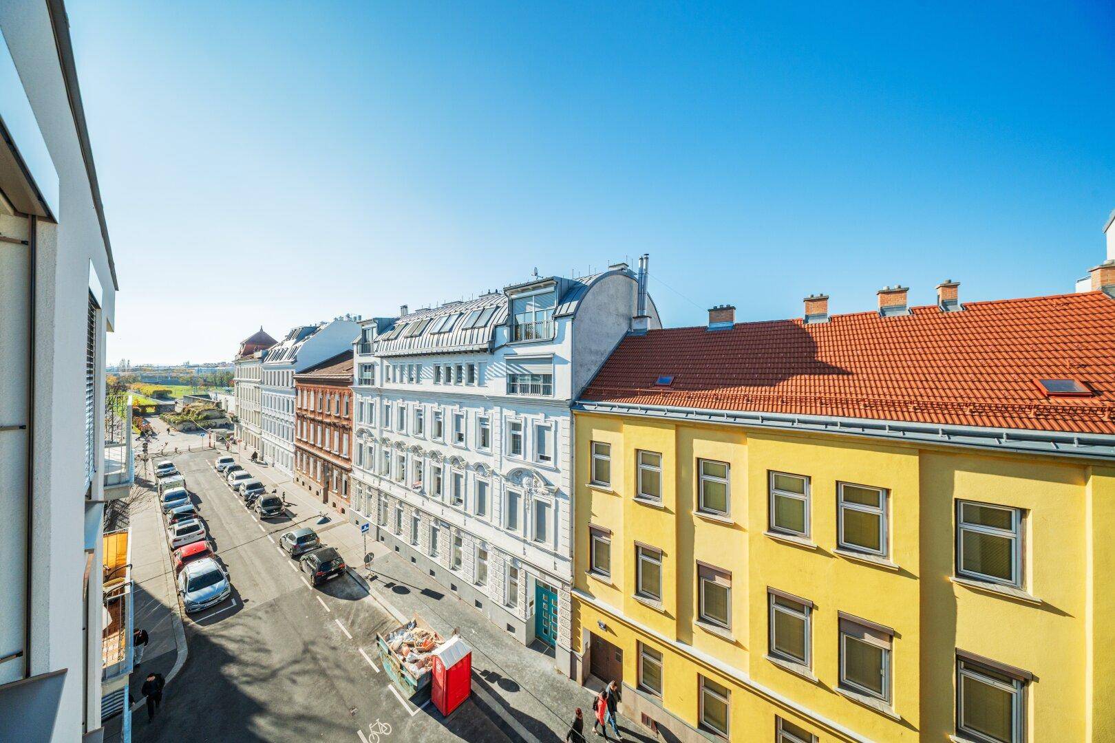 Weitläufiger Blick von einem Balkon auf die Stadtstraße mit historischen und modernen Gebäuden.