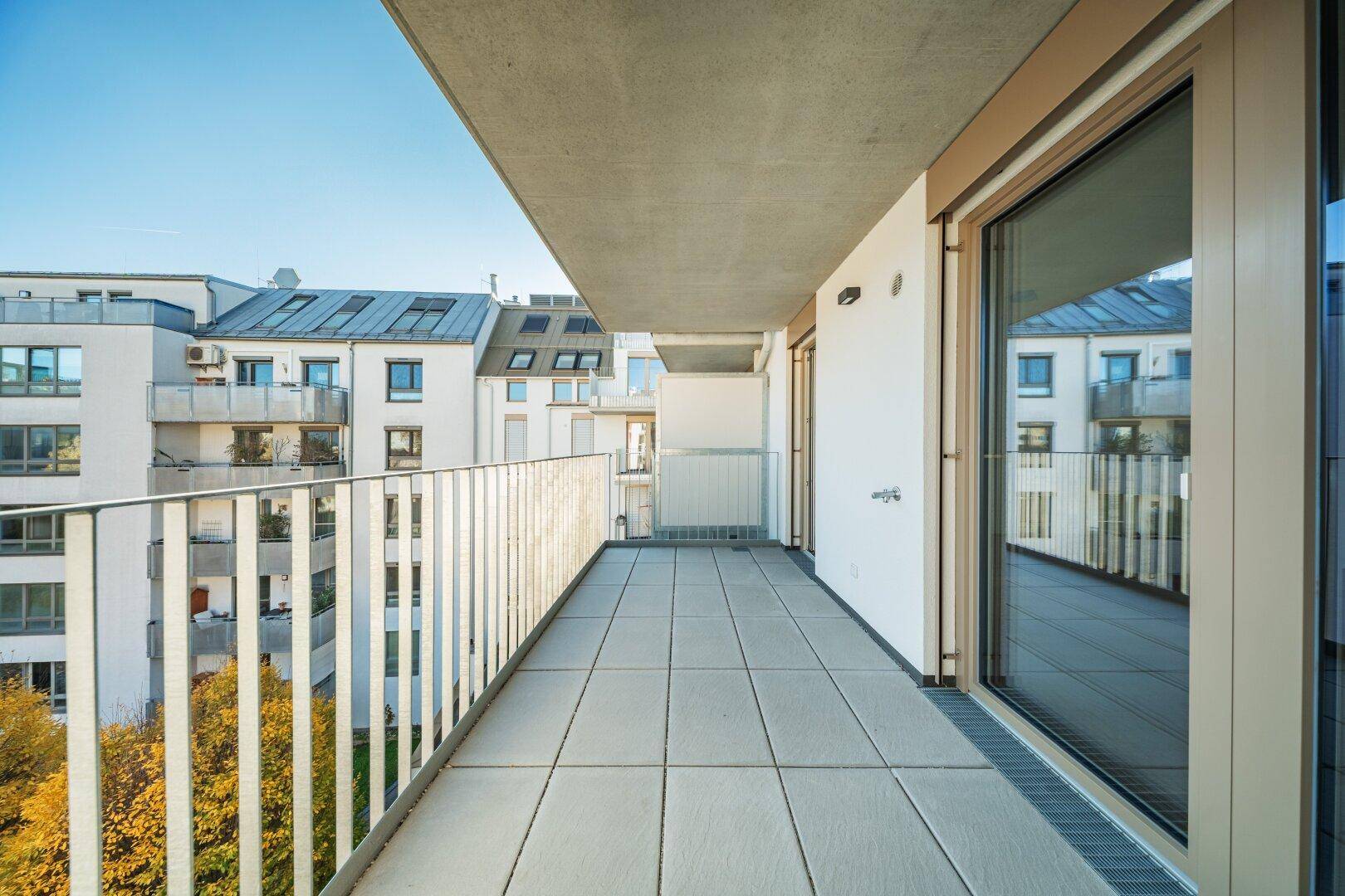 Langer Balkon mit Fliesenboden und Blick auf die Stadt, ideal für Entspannung.