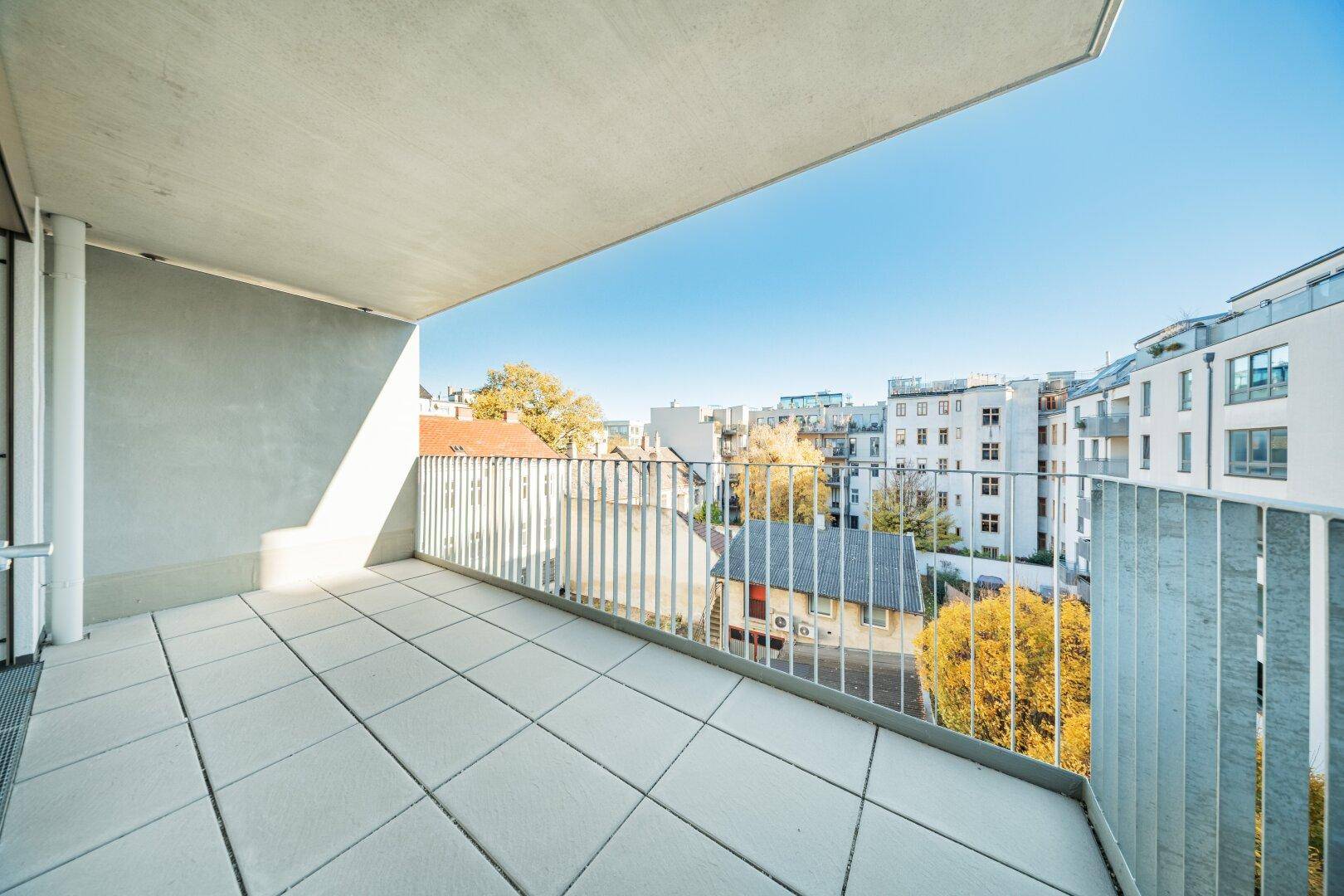 Geräumiger Balkon mit Fliesenboden und Blick auf die umliegenden Gebäude.