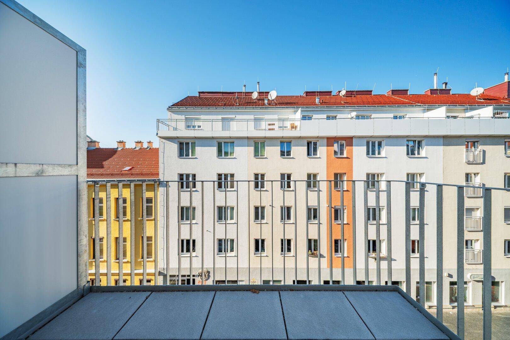 Fassadenansicht von Wohngebäuden mit Balkonen und Fenstern unter blauem Himmel.