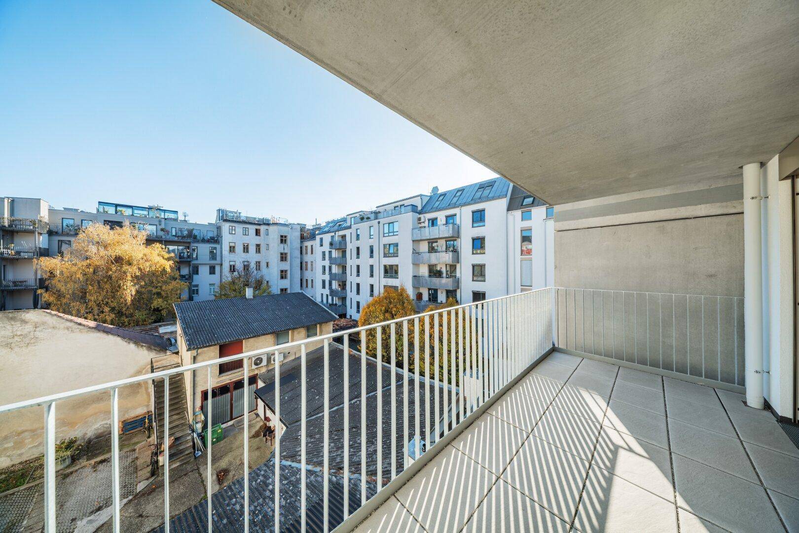 Sonniger Balkon mit Fliesenboden und weitem Blick auf die umliegende Stadtlandschaft.