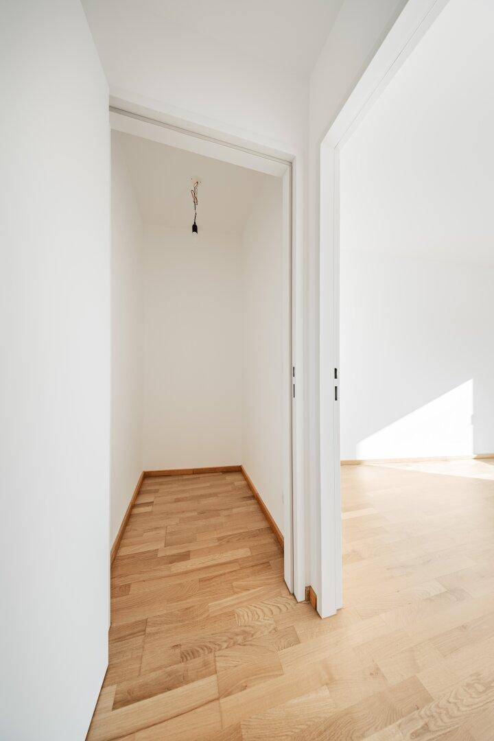 Kleiner Abstellraum mit Holzboden und weißen Wänden.
